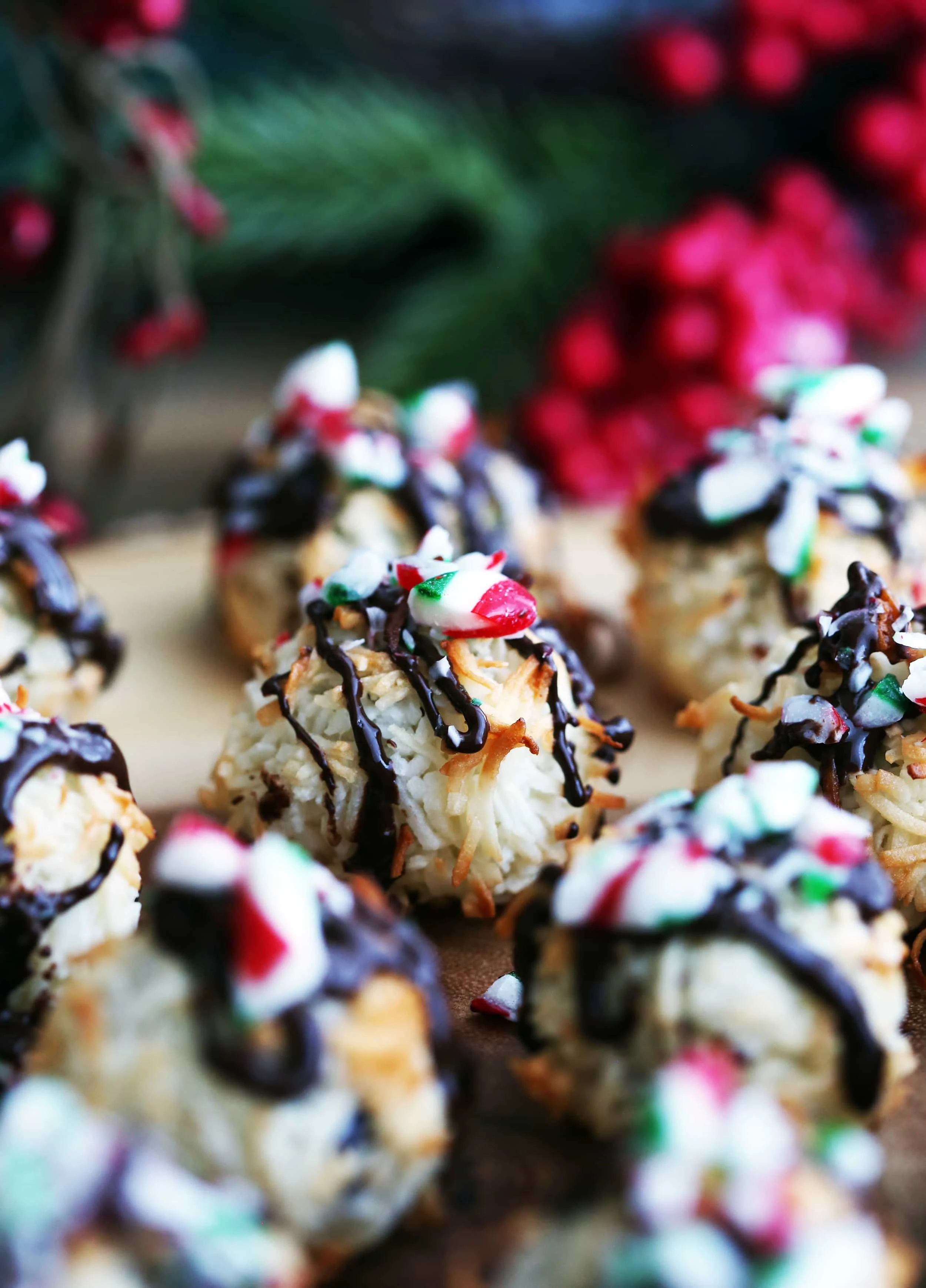 A closeup view of a single Peppermint Chocolate Coconut Macaroon surrounded by more macaroons on a wooden platter.