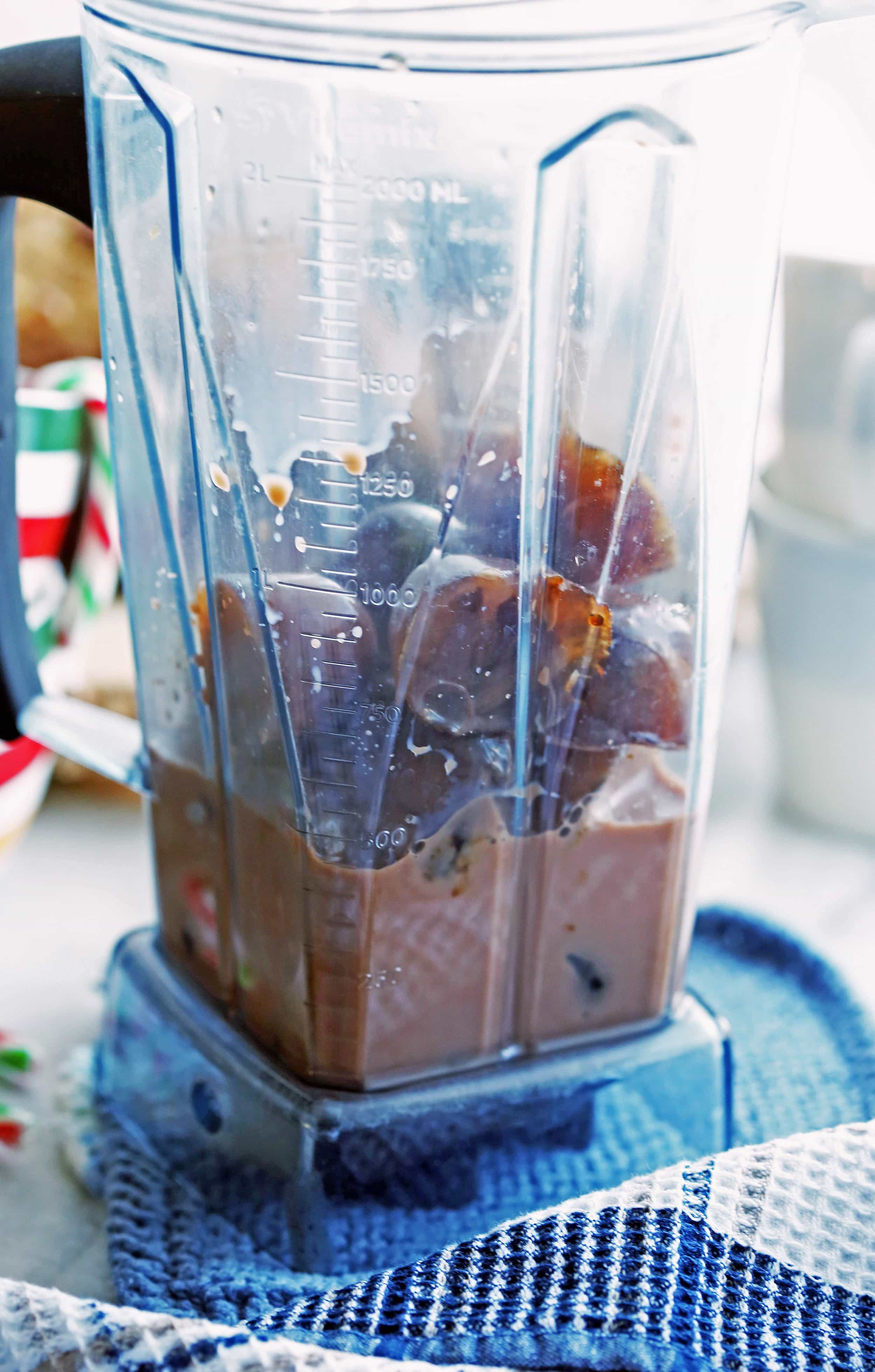 Frozen coffee cubes, chocolate milk, and peppermint extract in a clear blender container.