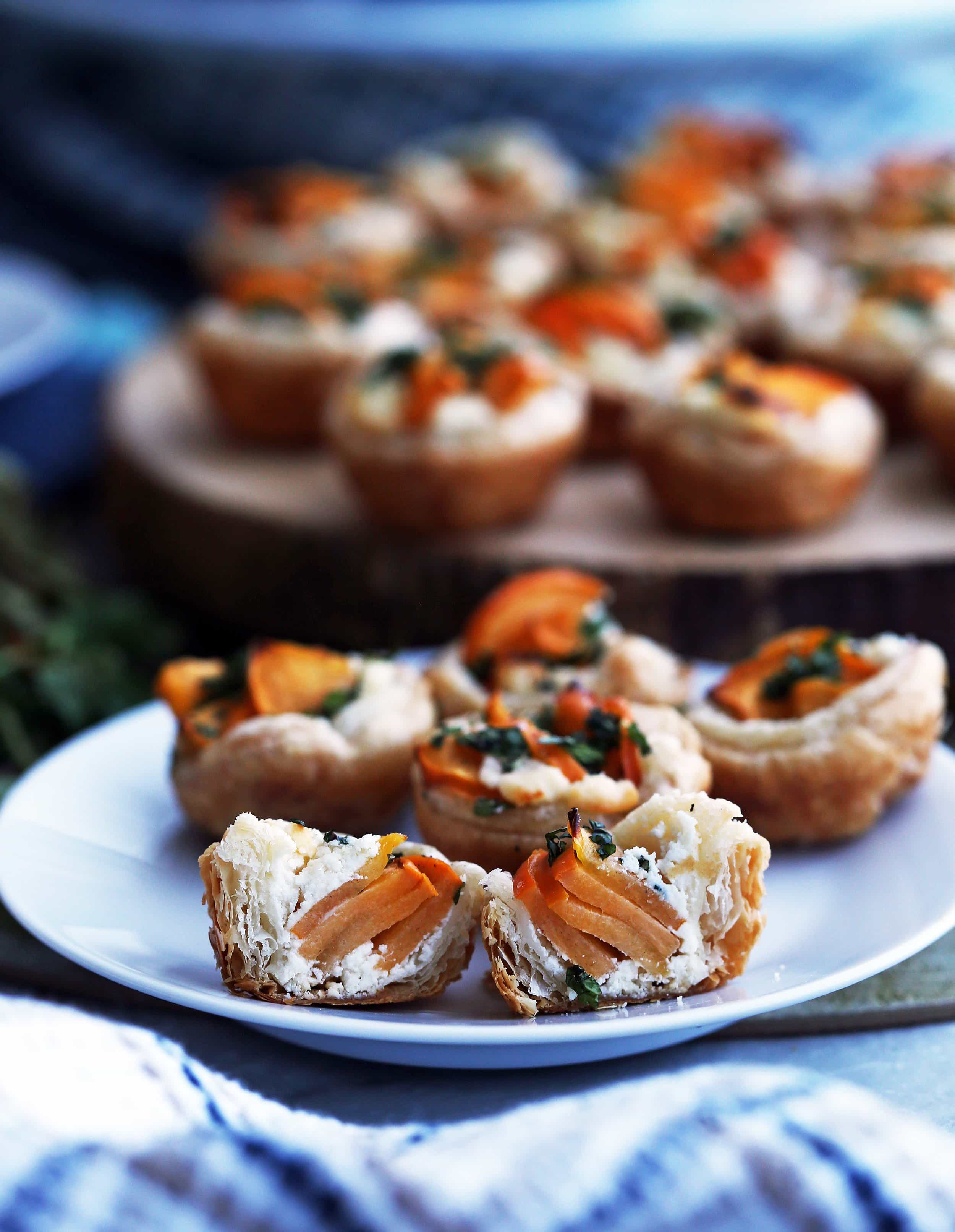 Five Persimmon Goat Cheese Tartlets on a white plate with one tartlet cut in half.