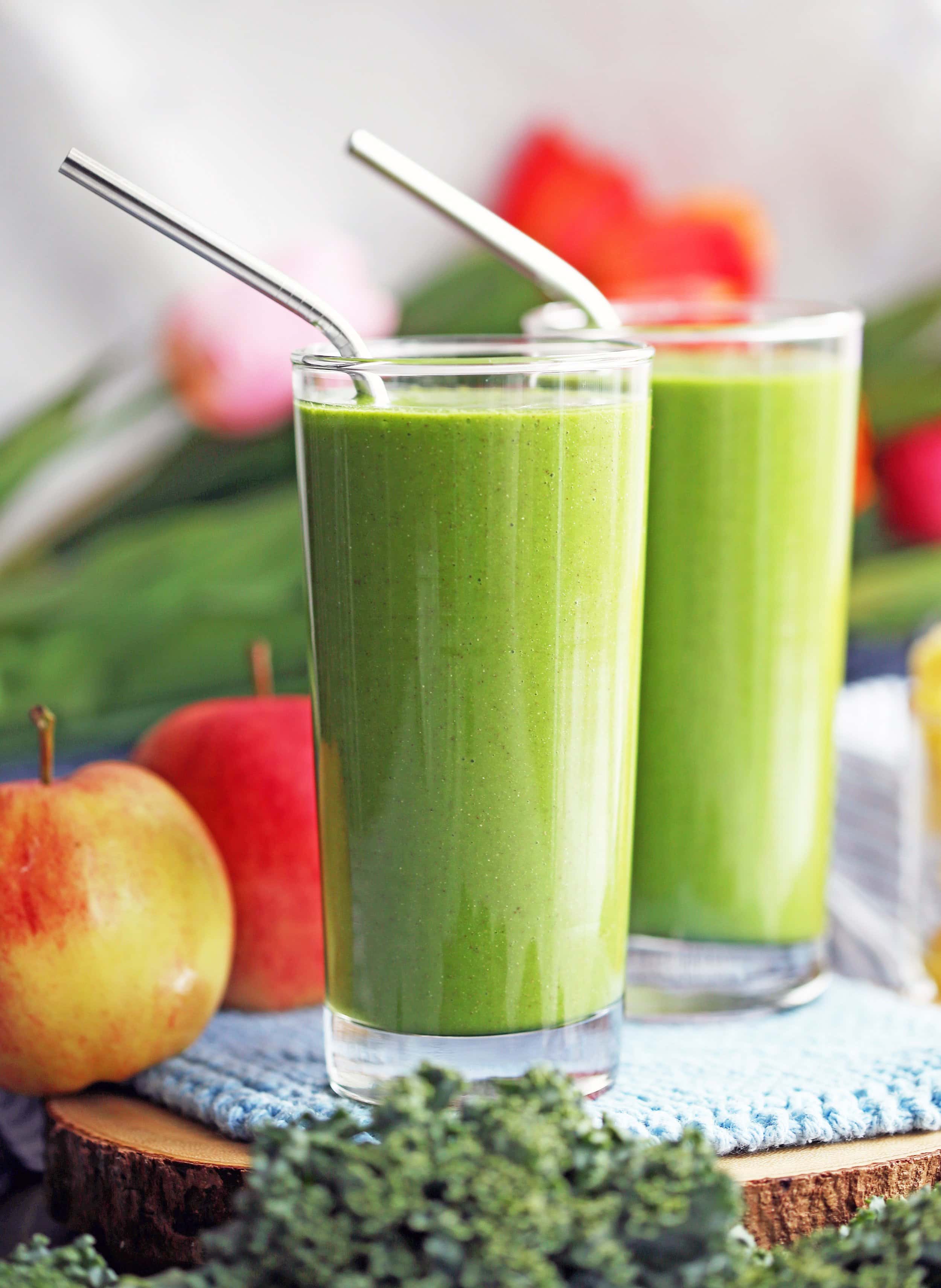 A side view of Kale Pineapple Chia Smoothies in two tall drinking glasses on a knitted blue cloth.