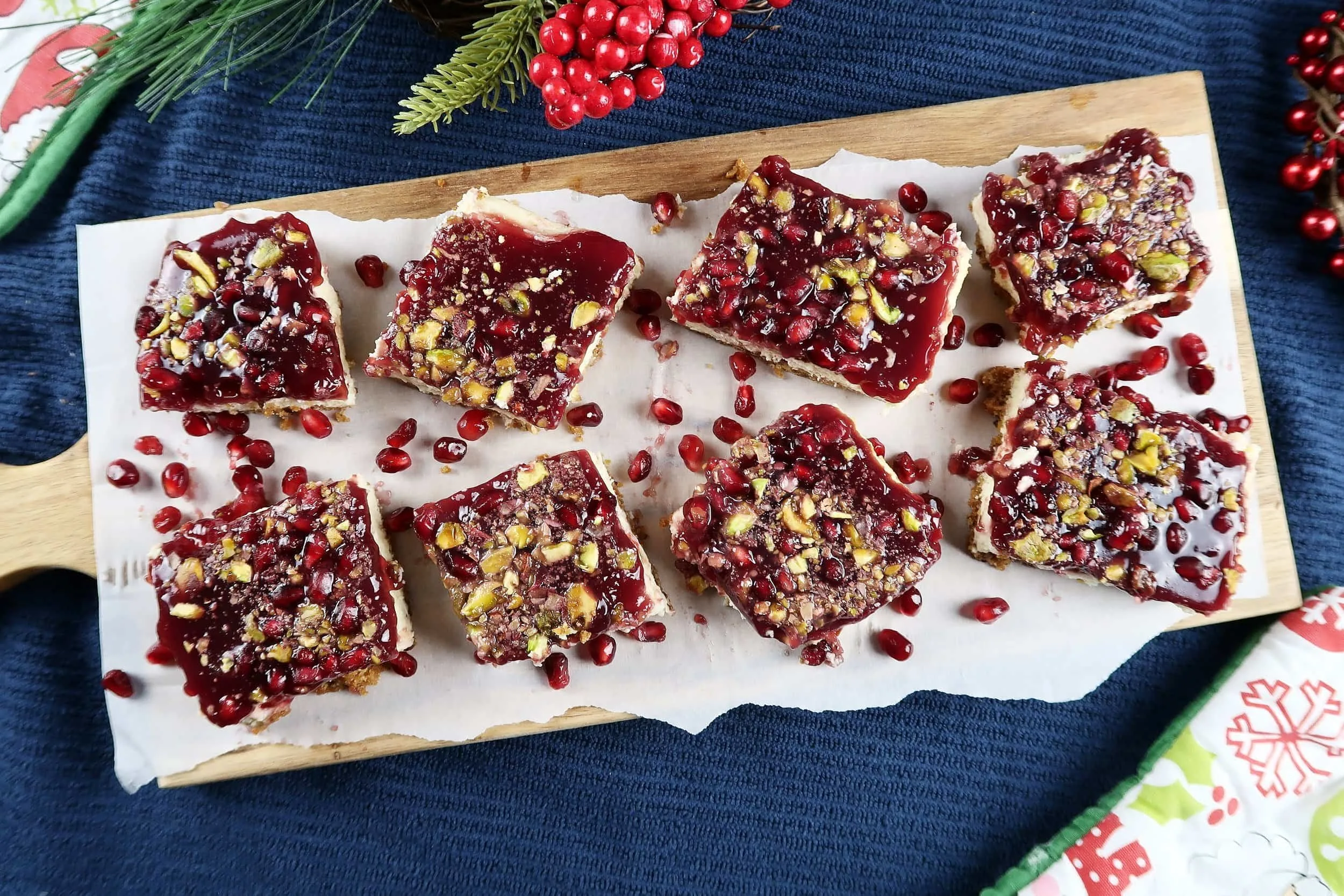 Pomegranate Pistachio Cheesecake Bars cut into squares and served on a cutting board