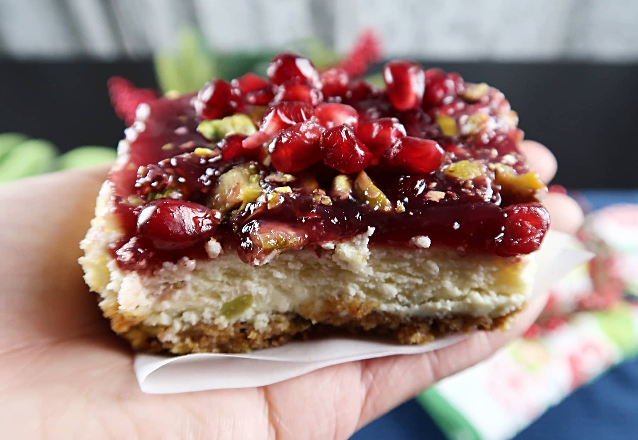 A side view of a pomegranate pistachio cheesecake bar.