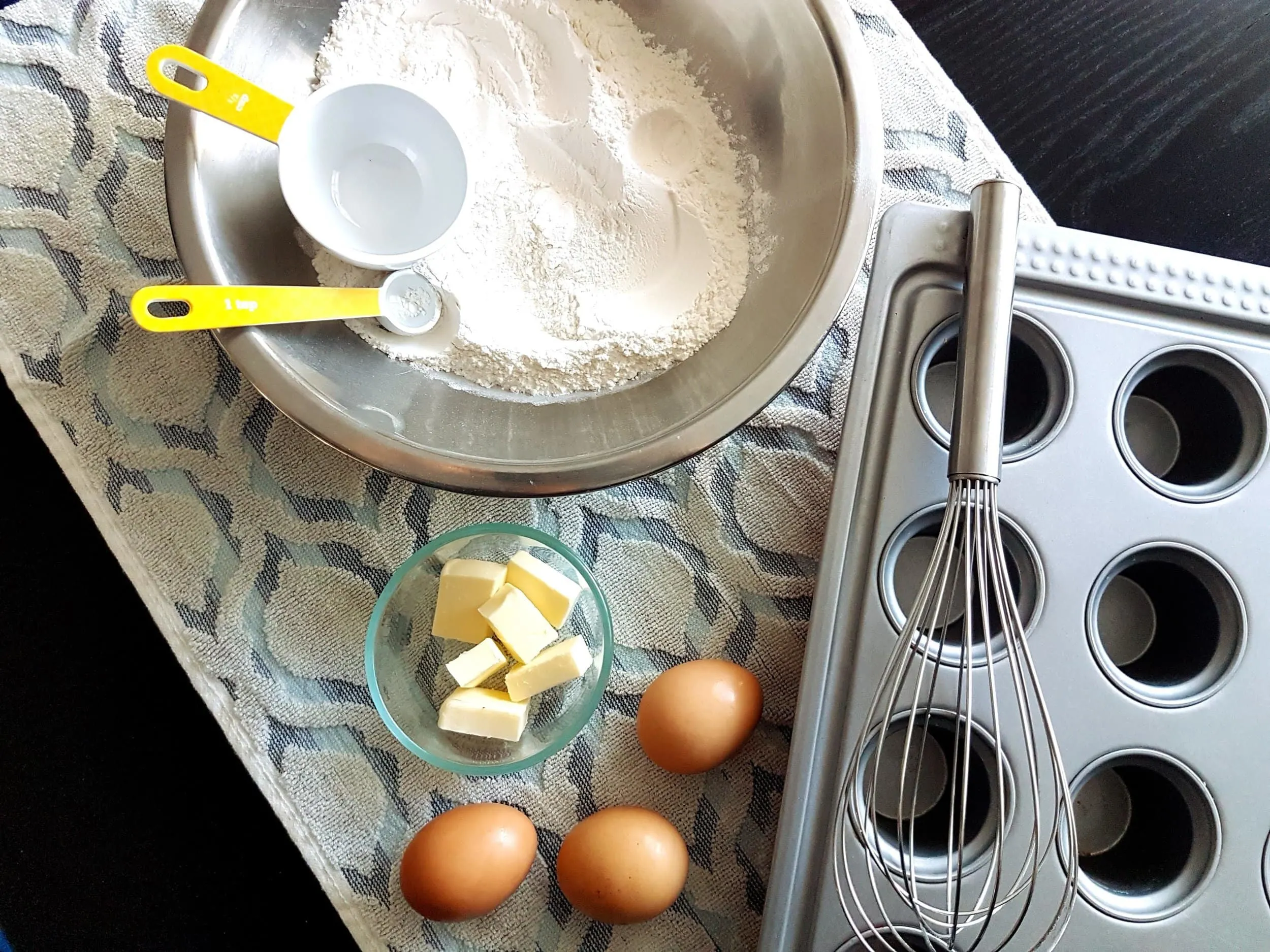 Flour, eggs, and butter, next to a popover pan.