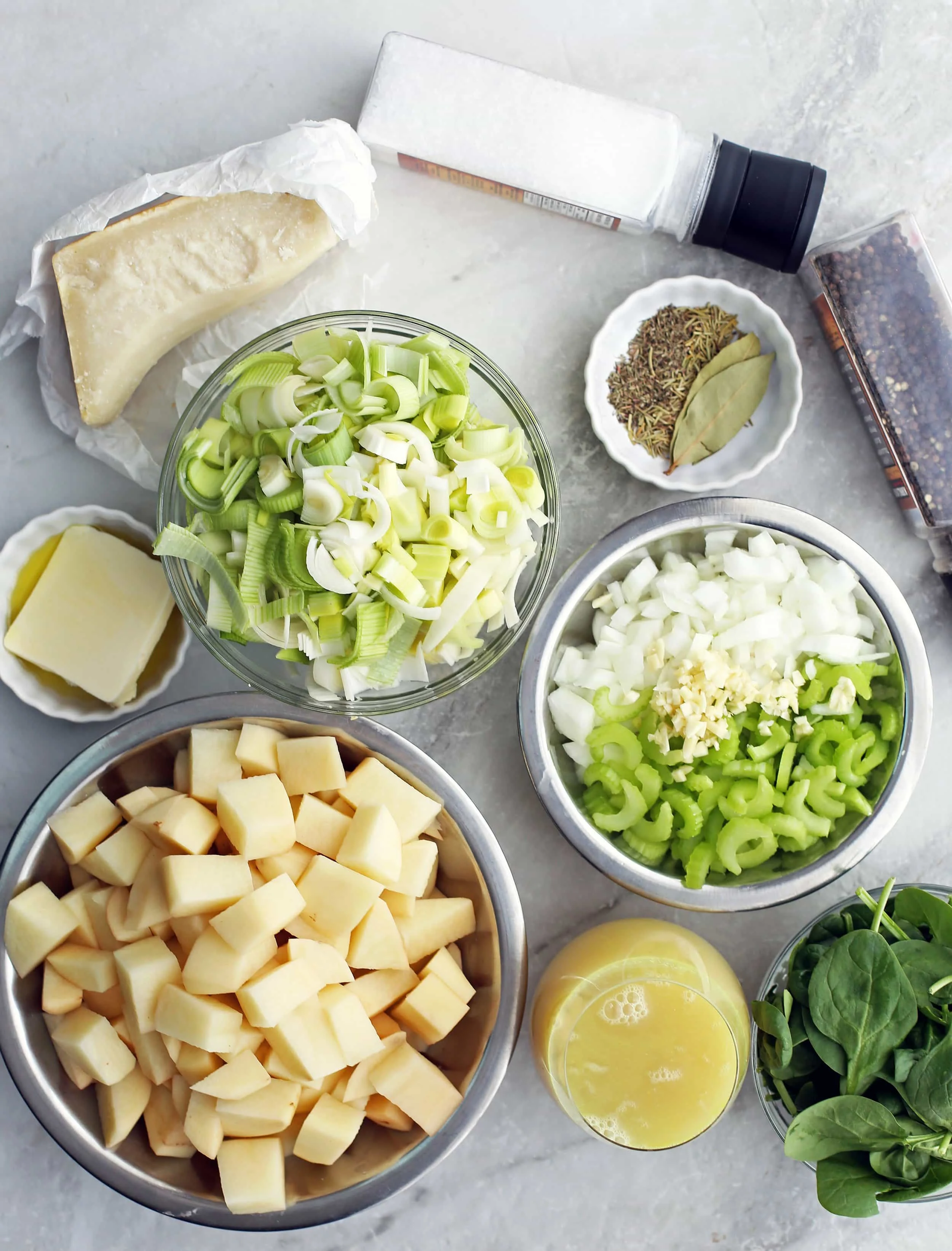 Bowls of potatoes, leeks, celery, onion, garlic, spinach, butter, broth, herbs, parmesan, salt, and pepper.