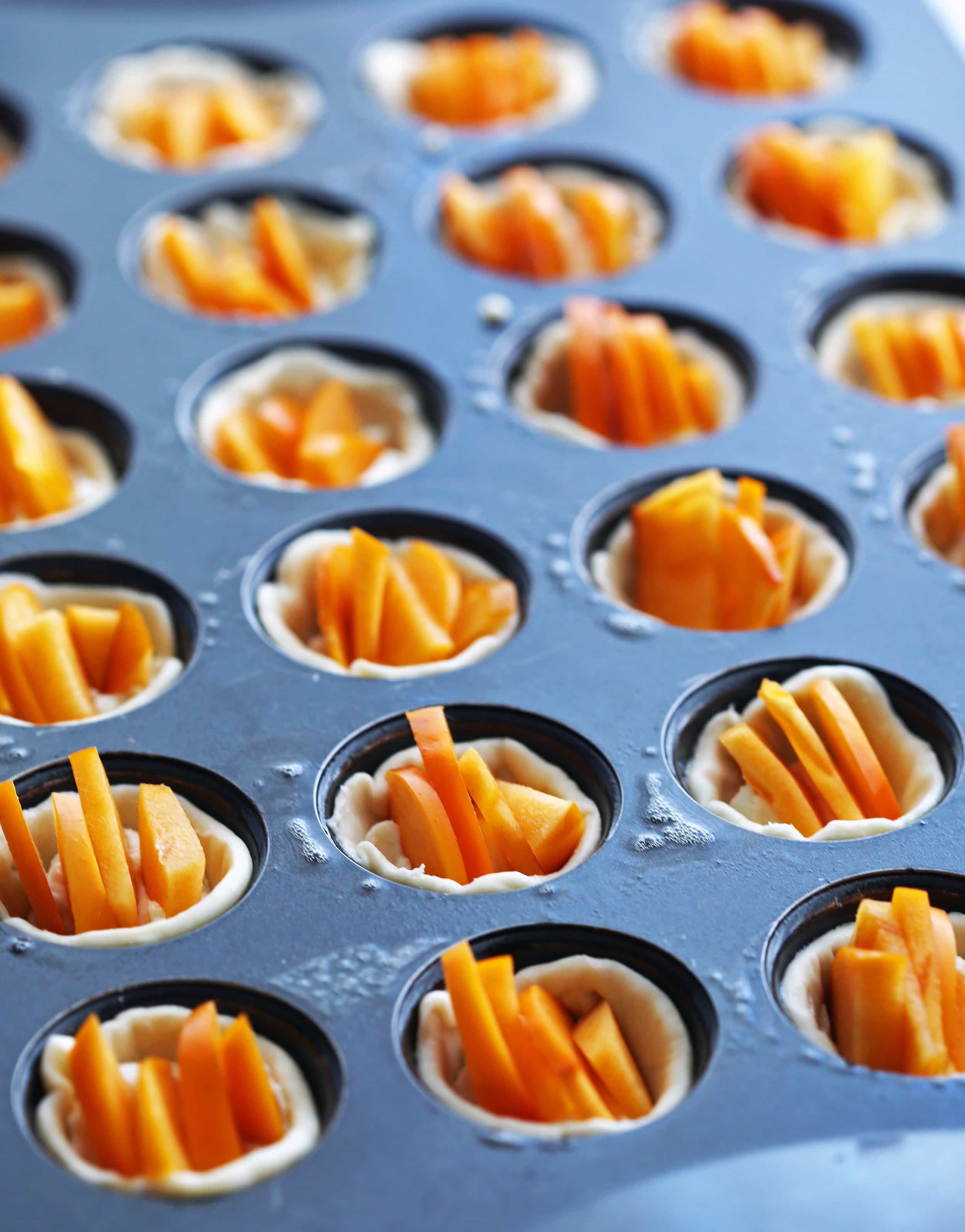 Unbaked Persimmon Goat Cheese Tartlets in a mini muffin pan.