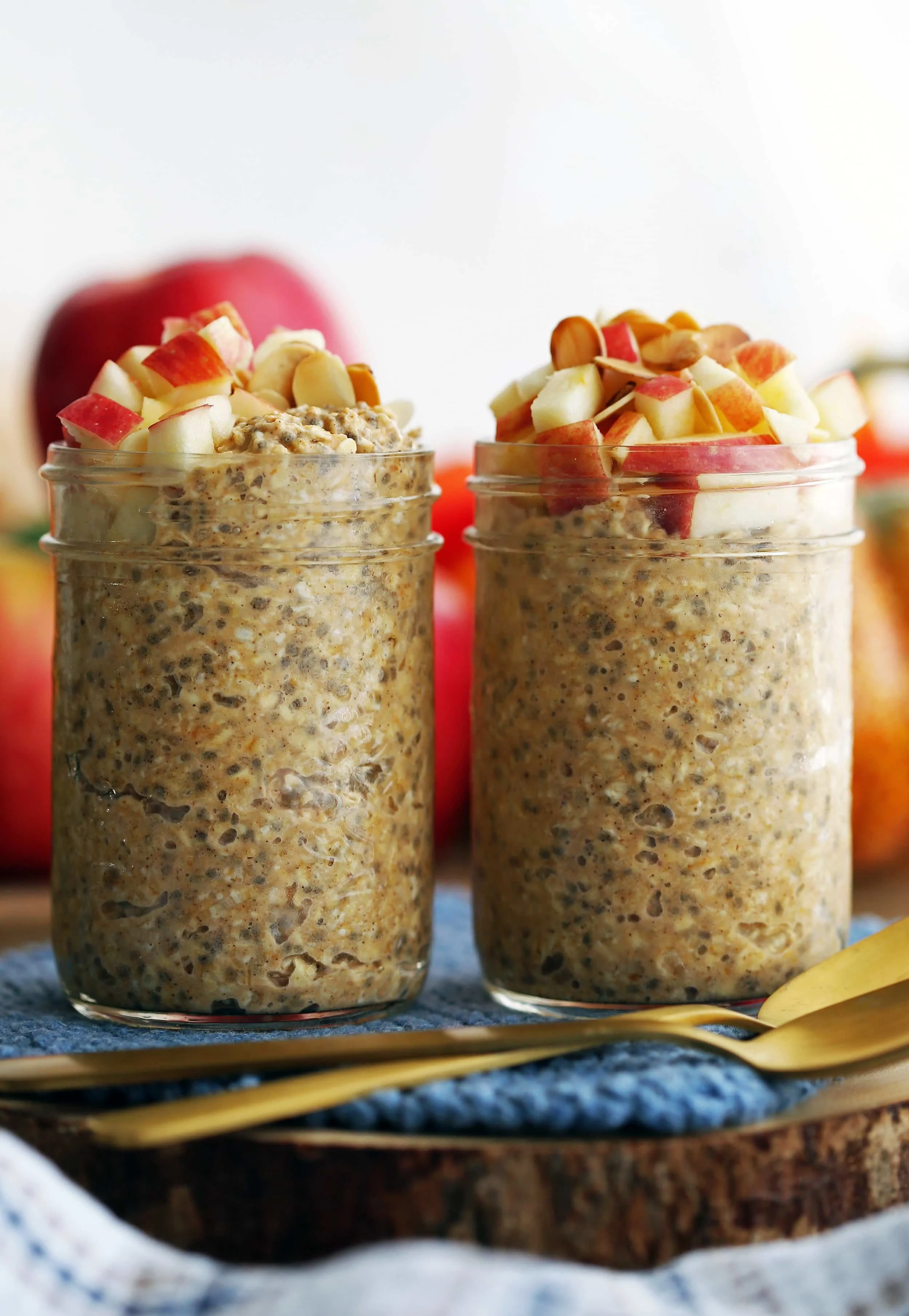 Closeup side view of two jars full of chai spiced pumpkin overnight oats with apple and almond topping.