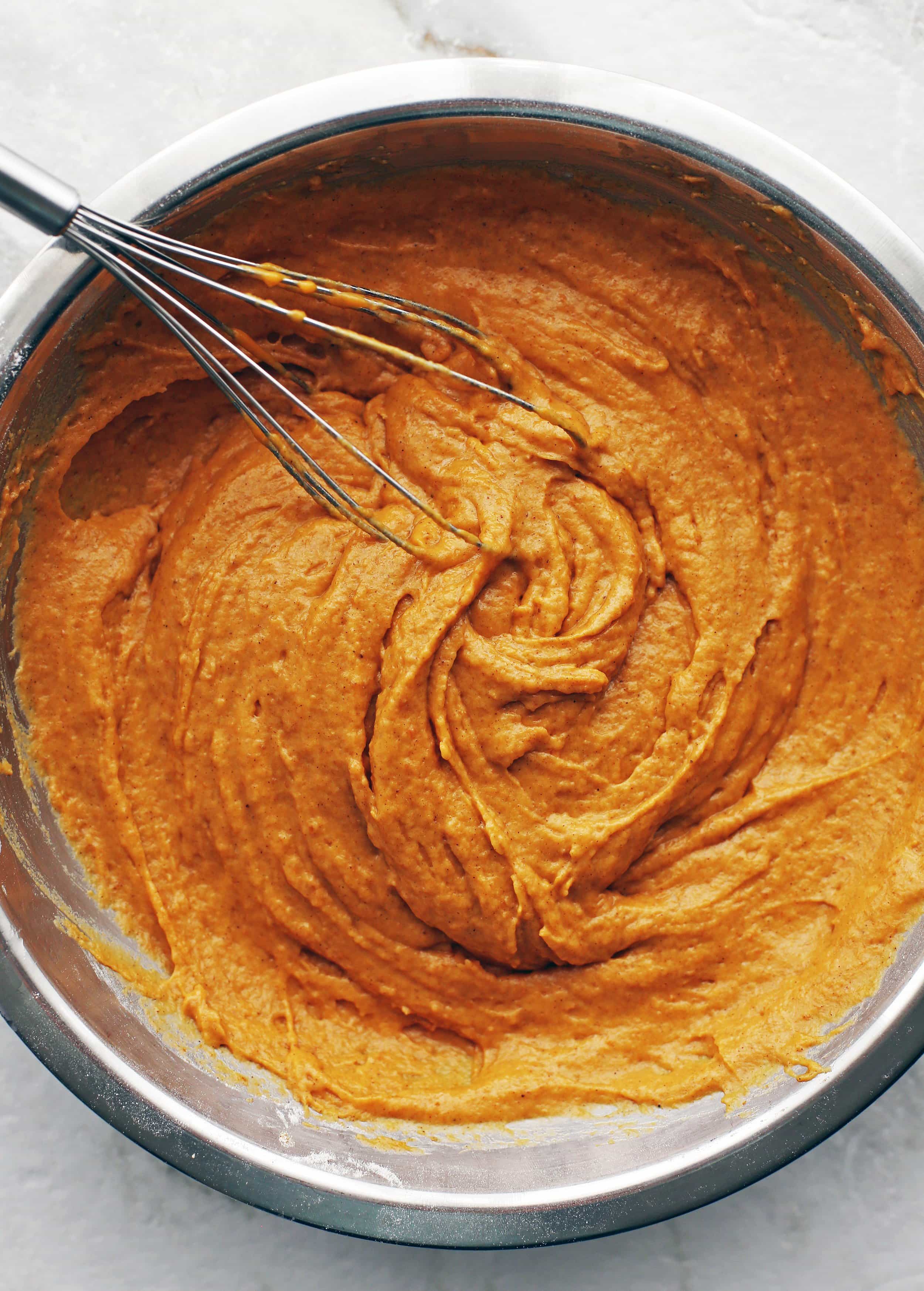Pumpkin muffin batter mixed together in a large metal bowl.