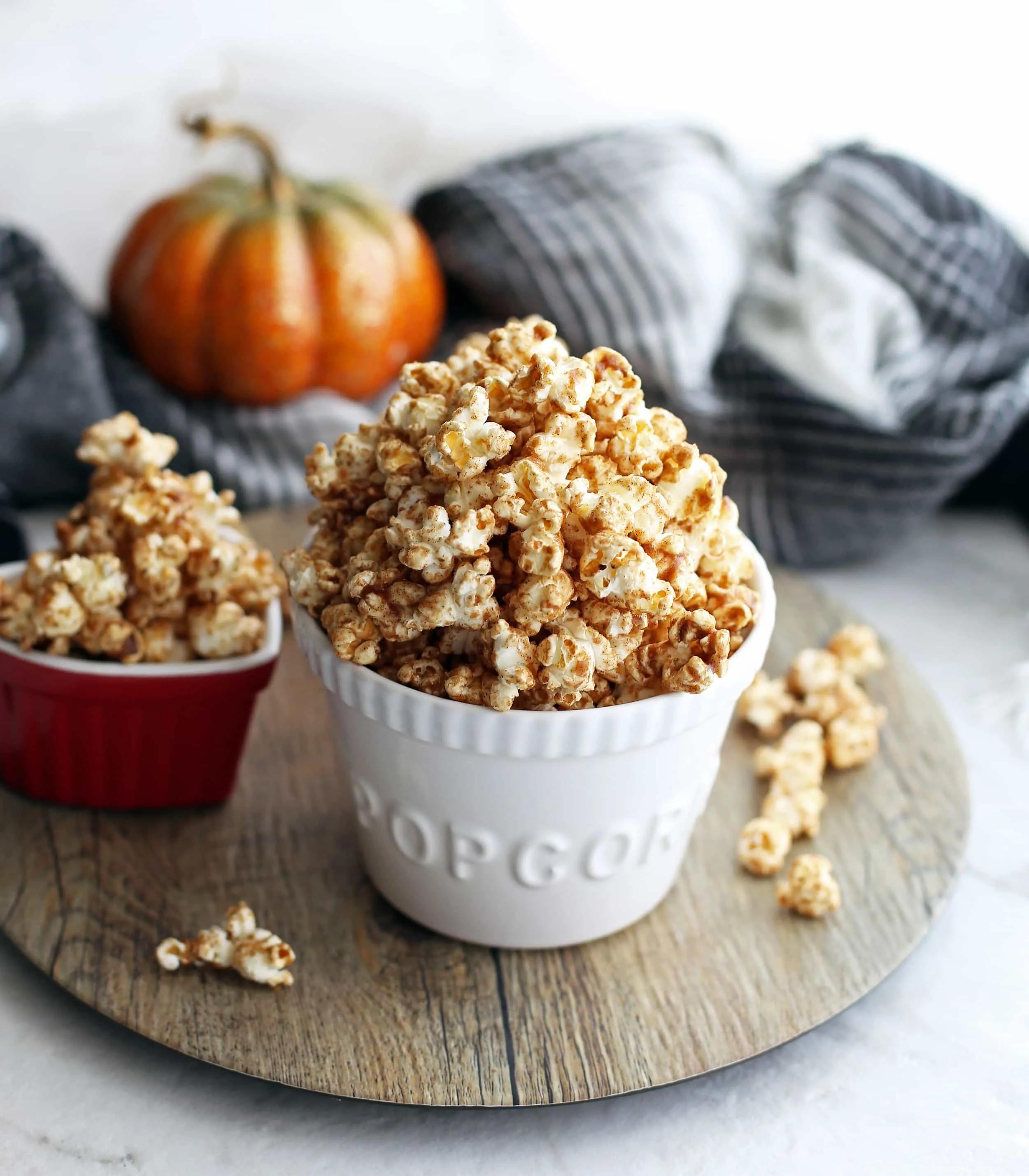 Two bowls filled with homemade pumpkin spice butterscotch popcorn on a wooden platter.