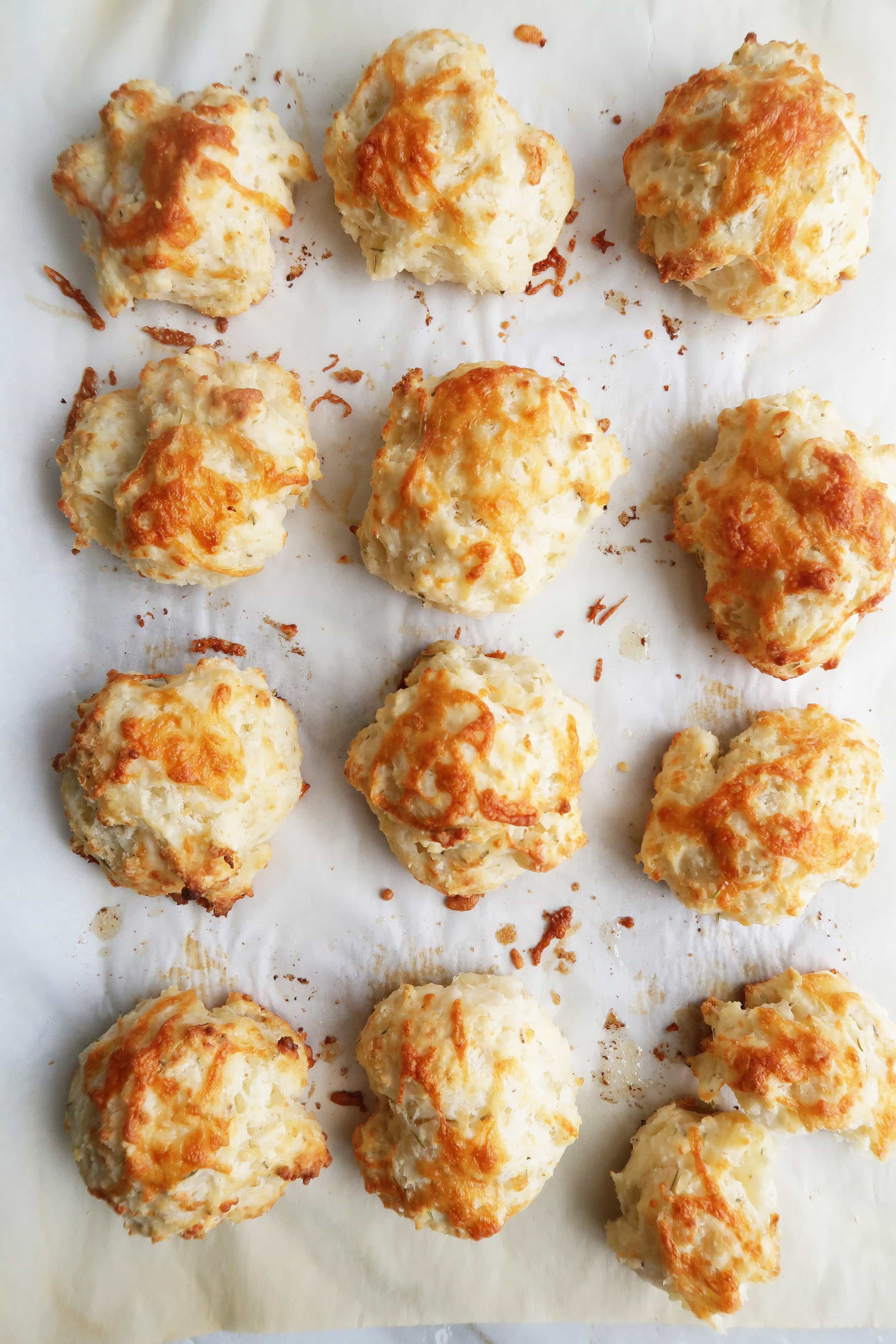 Freshly baked Quick Rosemary Cheddar Drop Biscuits on parchment paper.