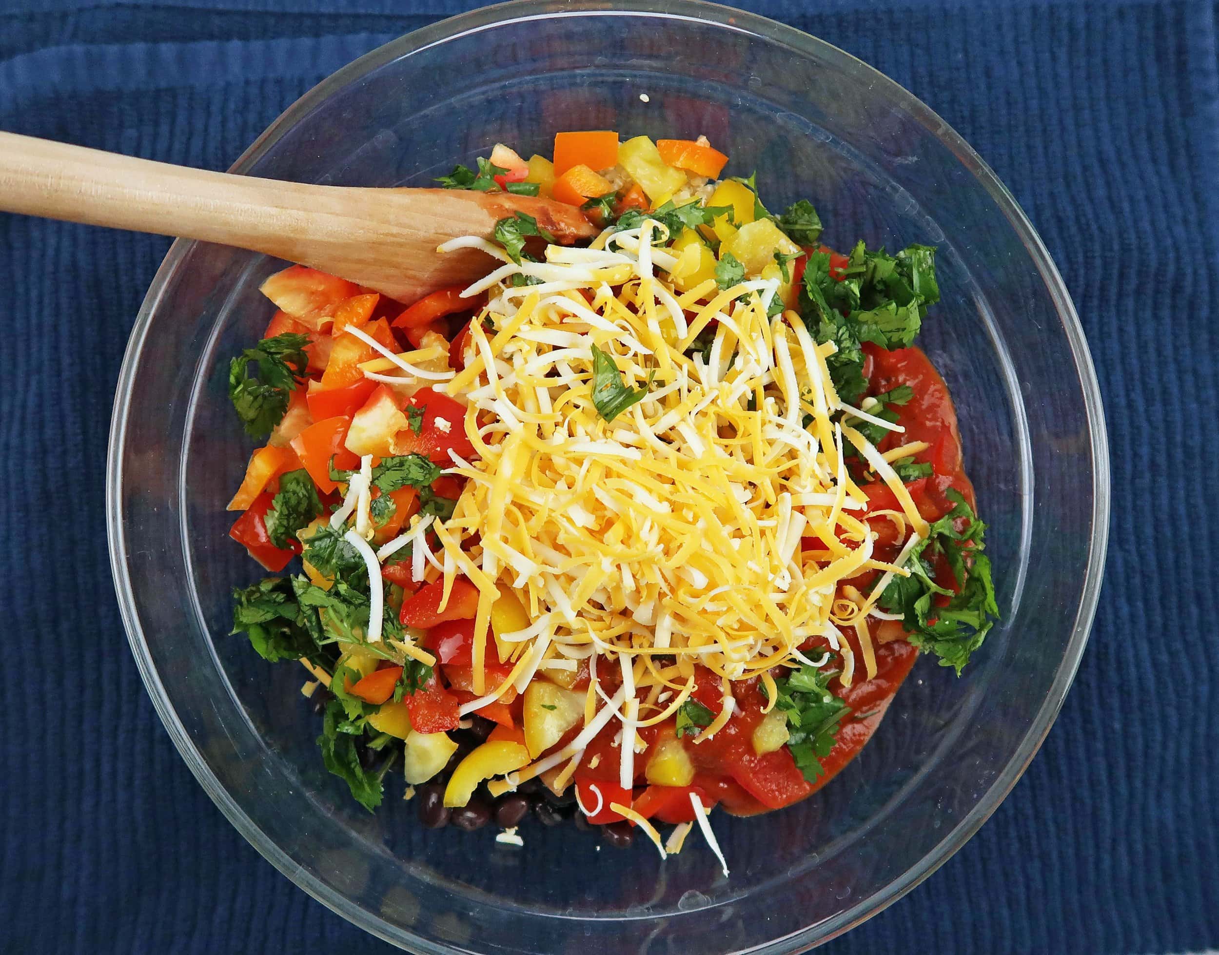 Quinoa, black beans, peppers, and cilantro in a bowl and topped with cheese.