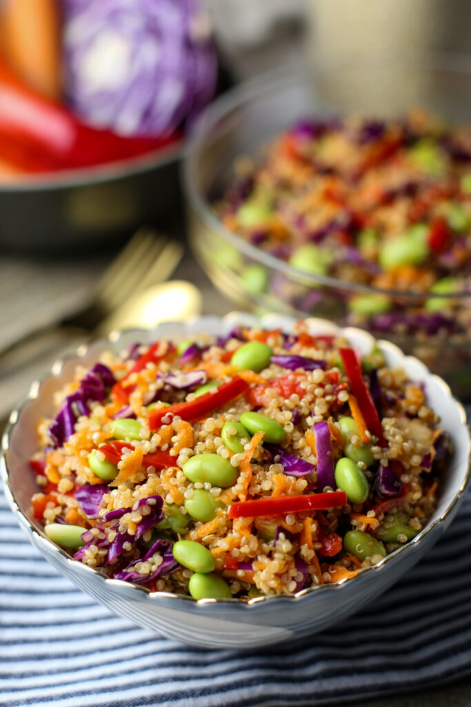 Quinoa edamame salad with peppers, cabbage, and carrots in a small blue and white bowl.