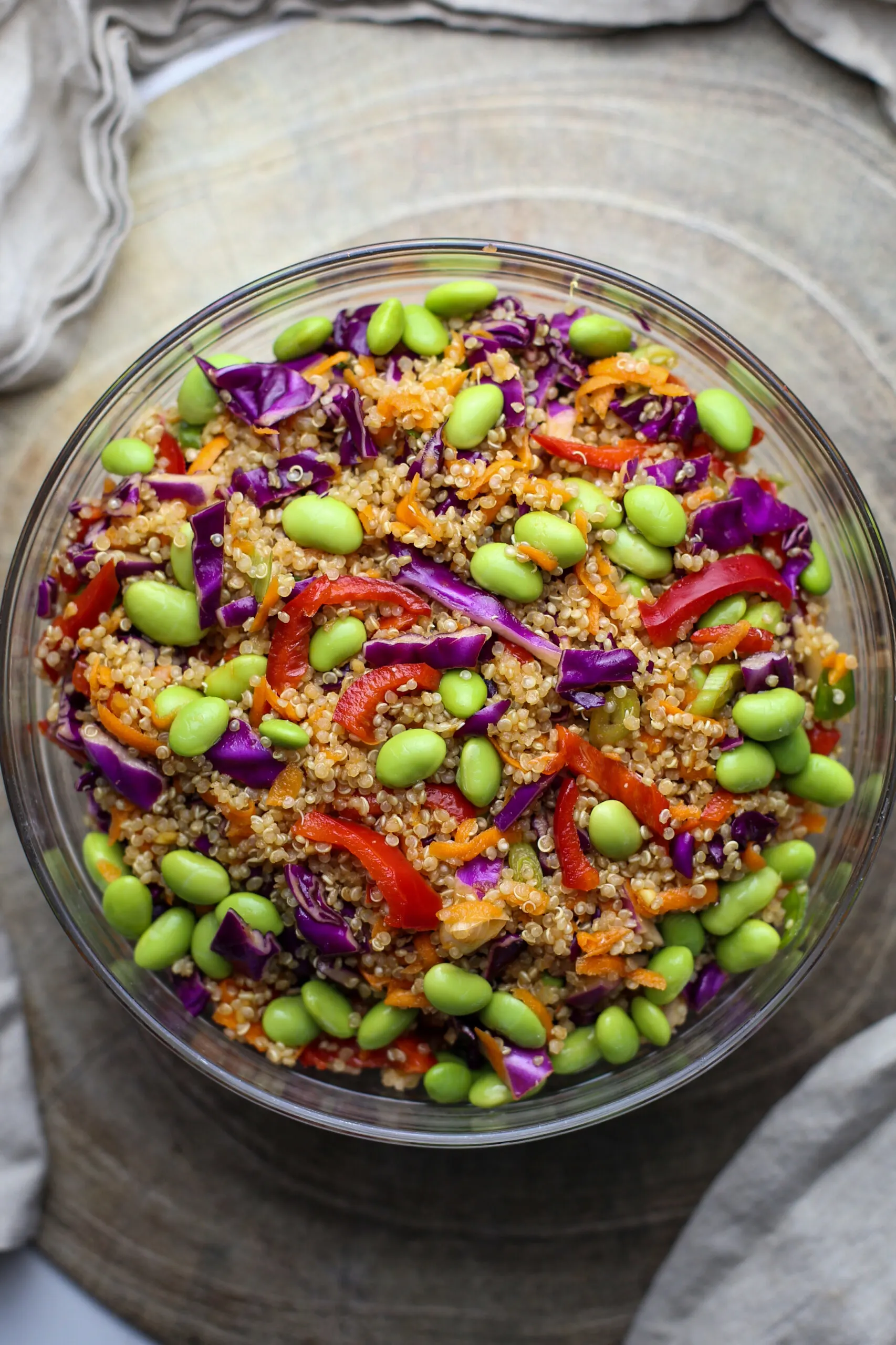 Quinoa edamame salad with peppers, cabbage, and carrots in a large glass bowl.