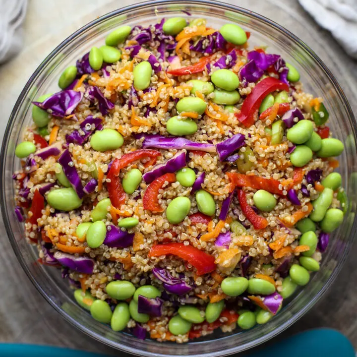 Quinoa edamame salad with peppers, cabbage, and carrots in a large glass bowl.