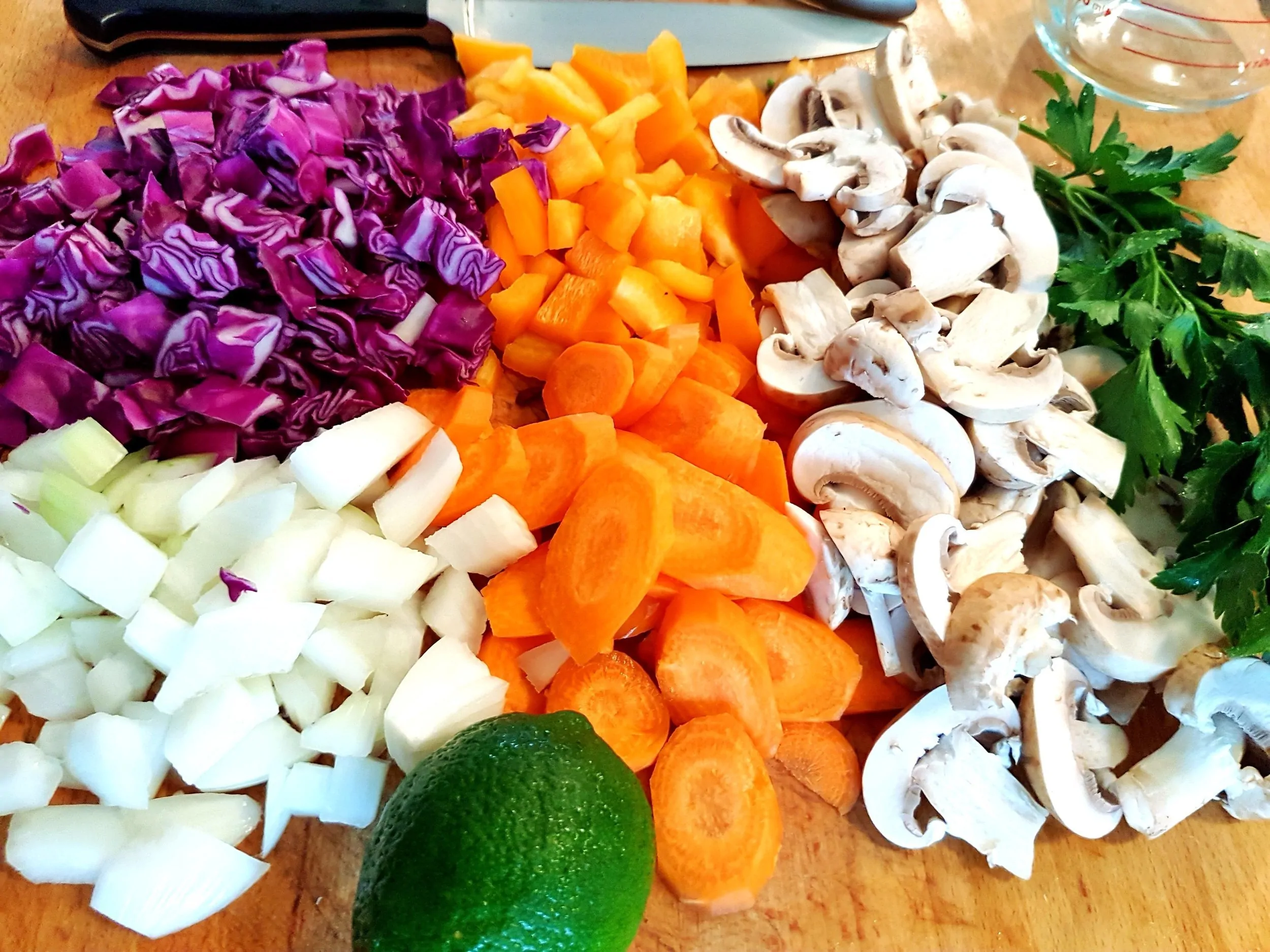 Onions, cabbage, carrots, and mushrooms lined up on a cutting board.
