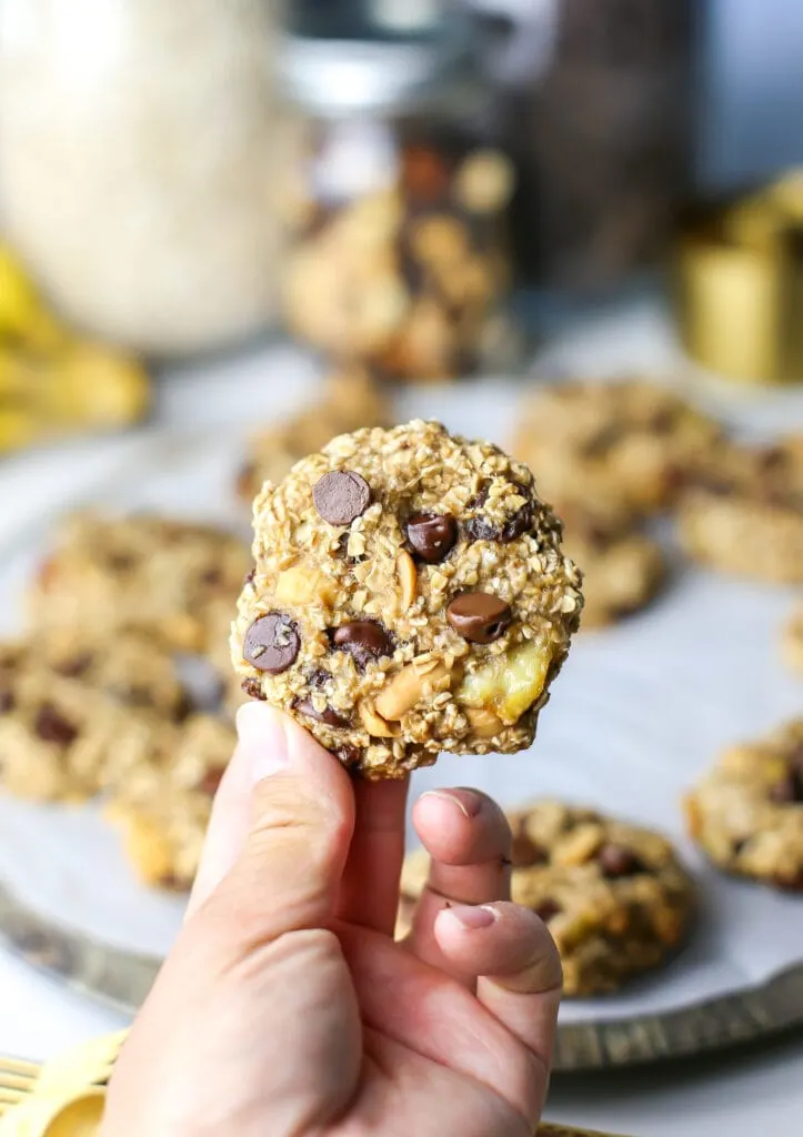 A single trail mix cookie held up by a person's hand.