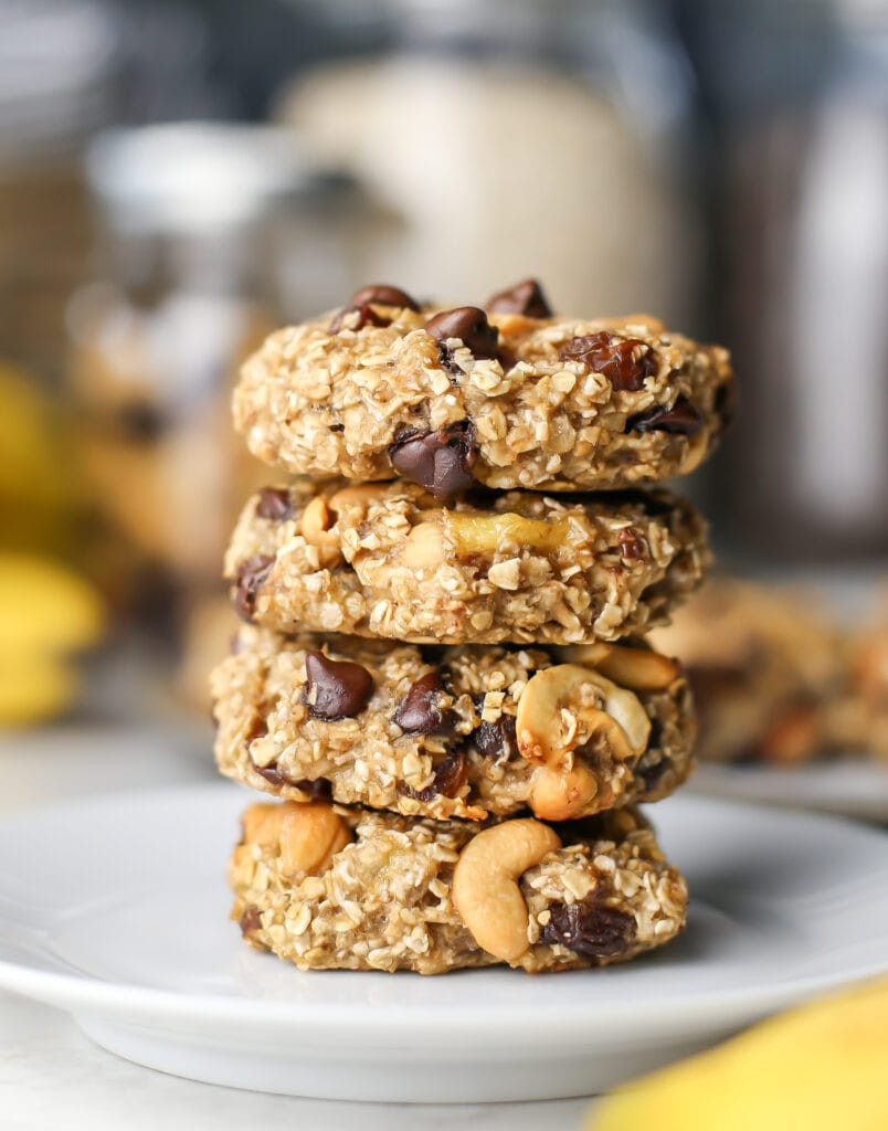 Four stacked trail mix cookies on a white plate.