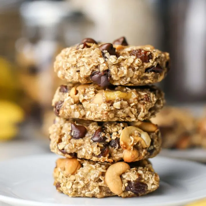 Four stacked trail mix cookies on a white plate.