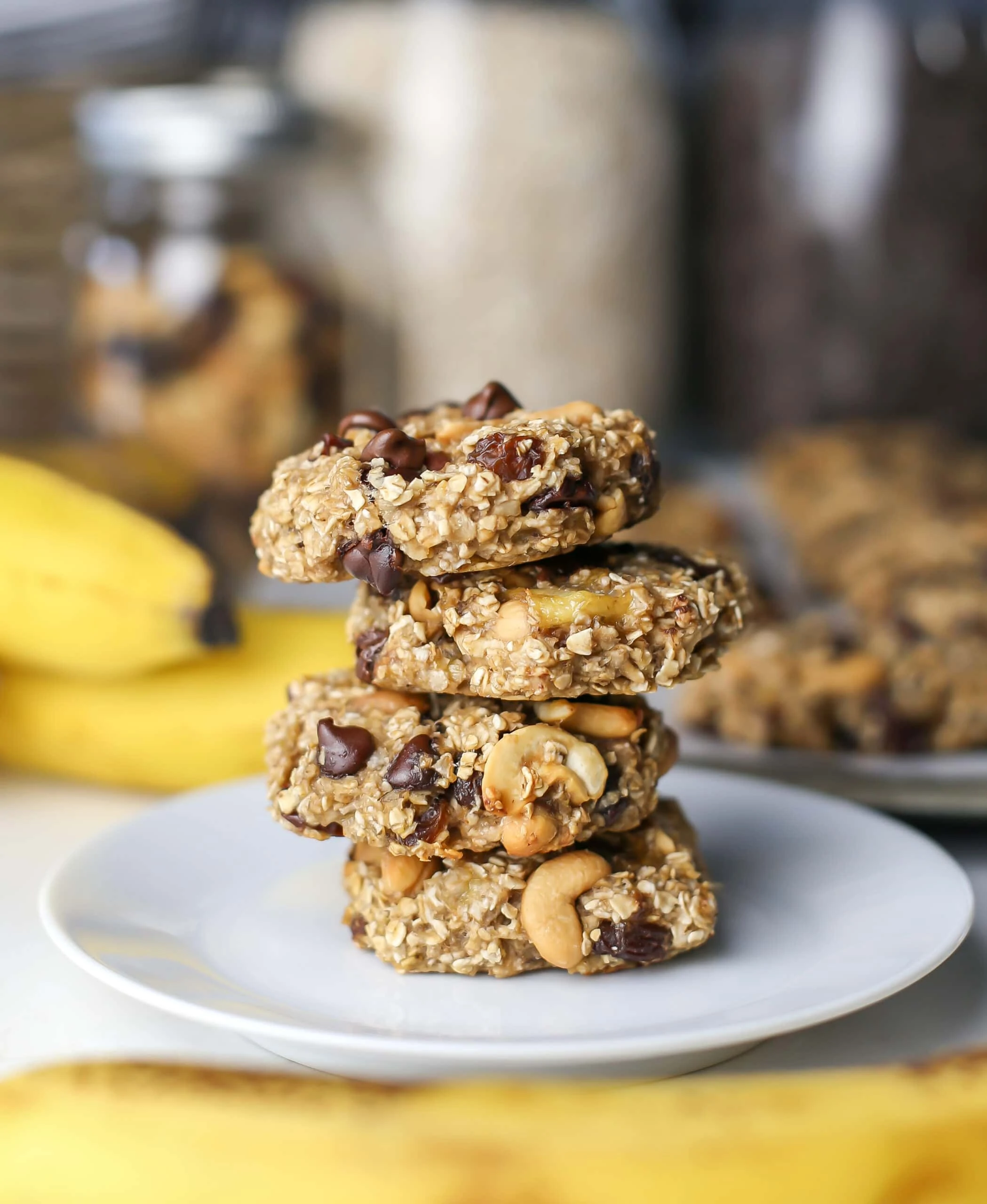 Four trail mix cookies placed on top of one another on a white plate.