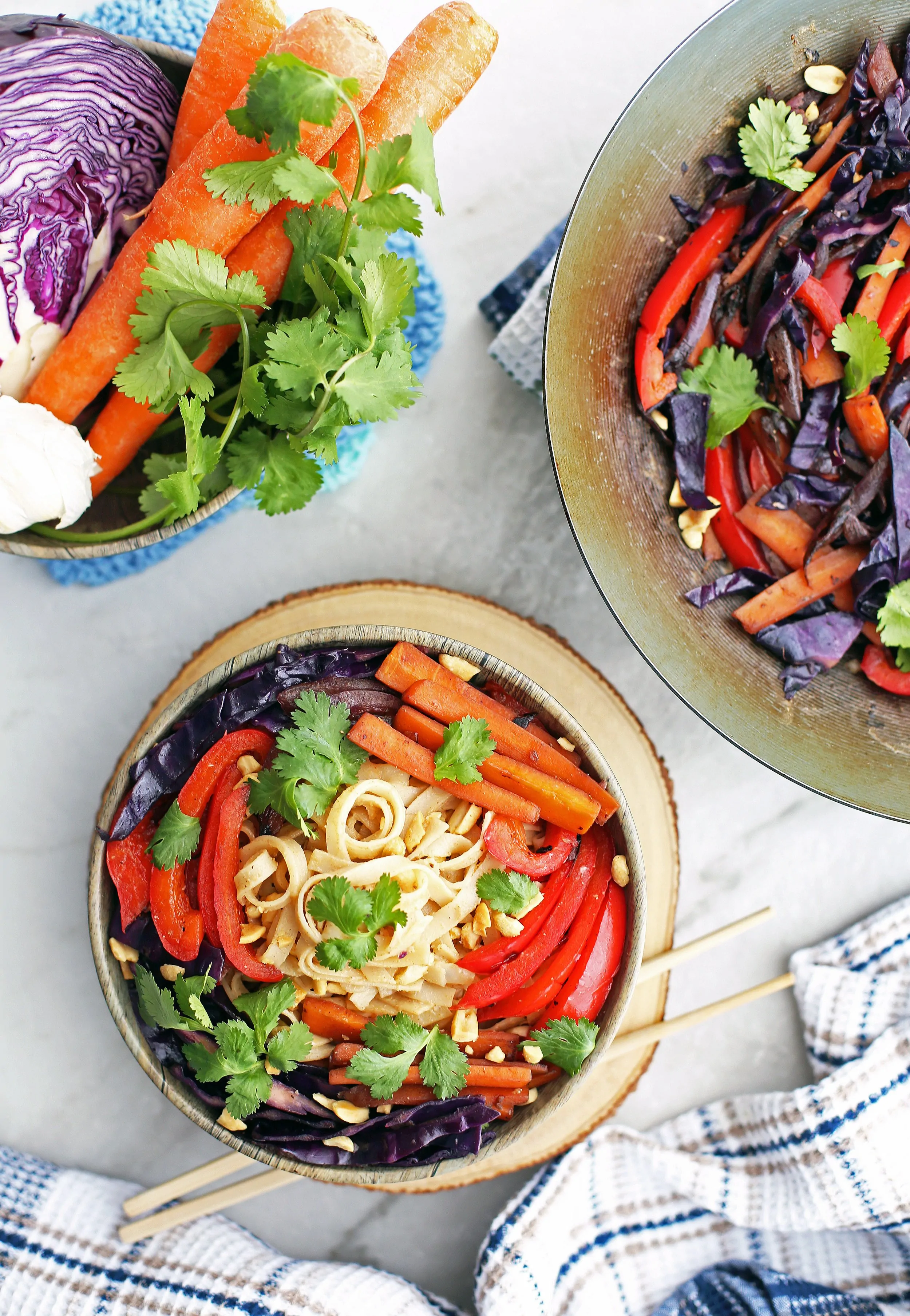 Stir-Fry Vegetables and Noodles with Peanut Sauce in a wooden bowl and in a wok; a bowl of vegetables to the side.