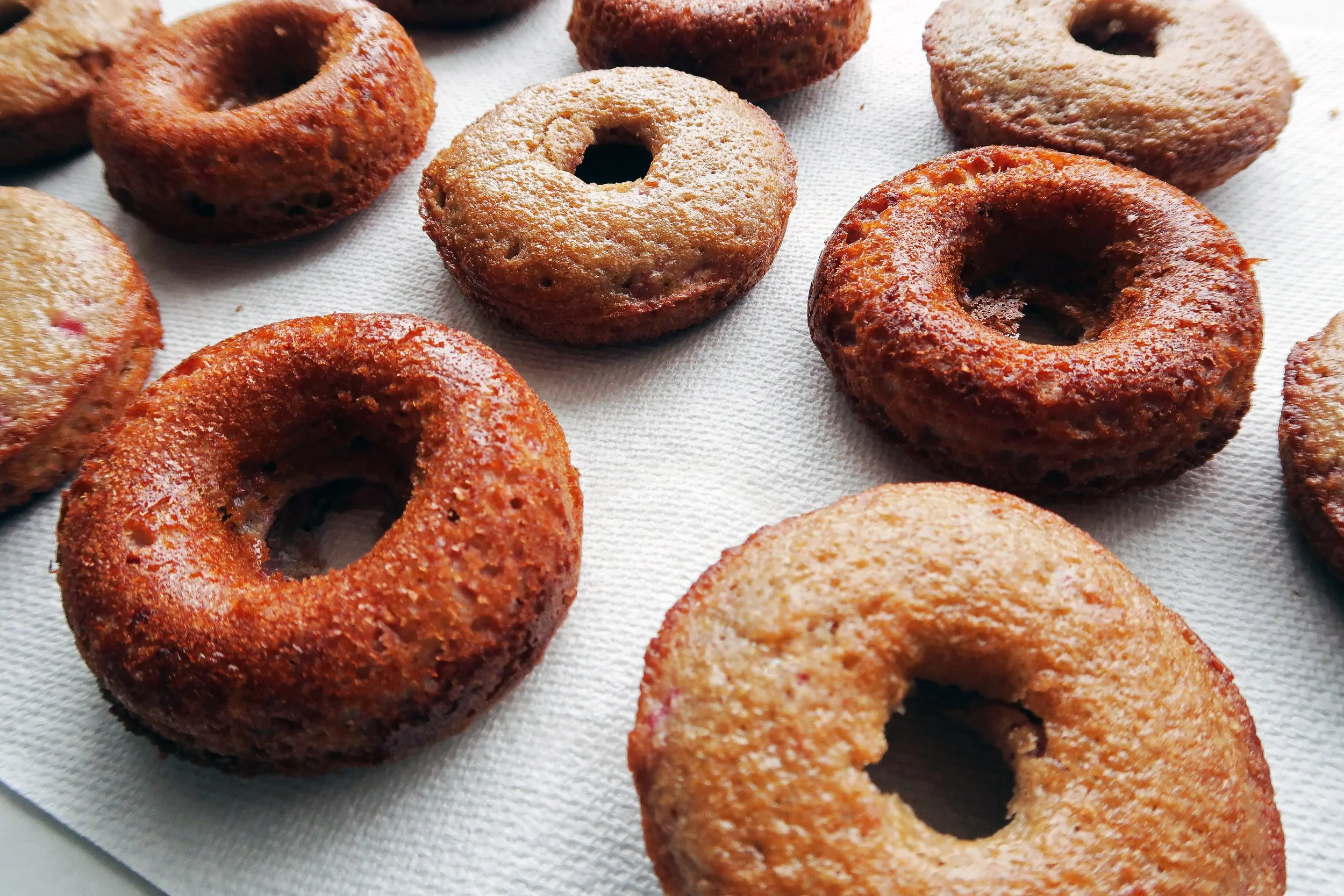 Freshly baked golden brown donuts on a paper towel.