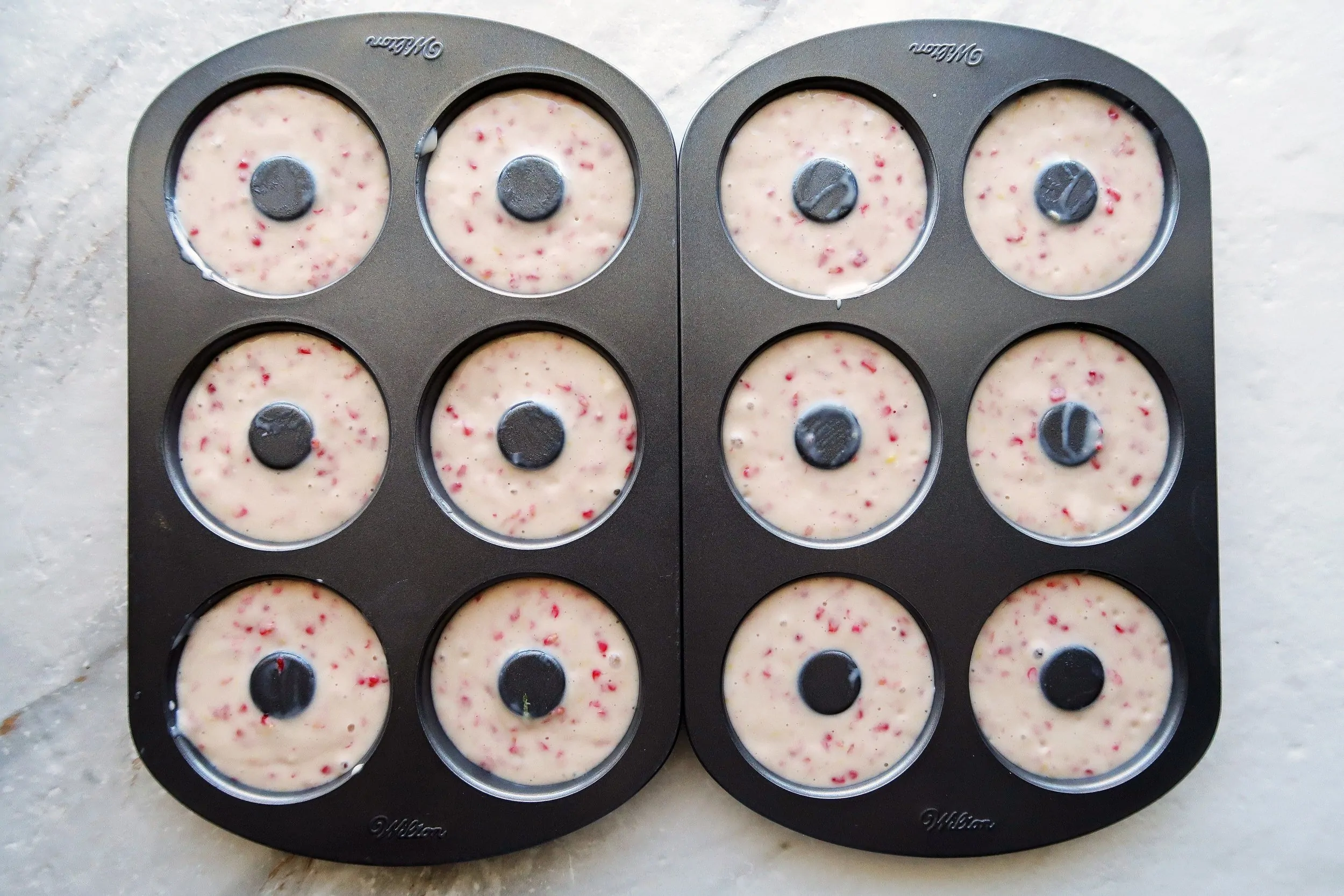 Donut pans filled with raspberry lemon donut batter.