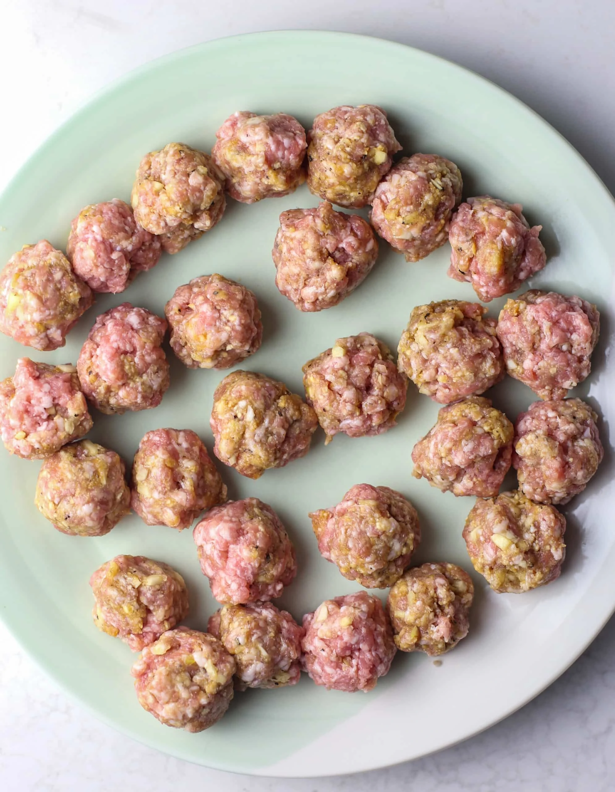 Overhead view of ginger pork meatballs on a green and white plate.