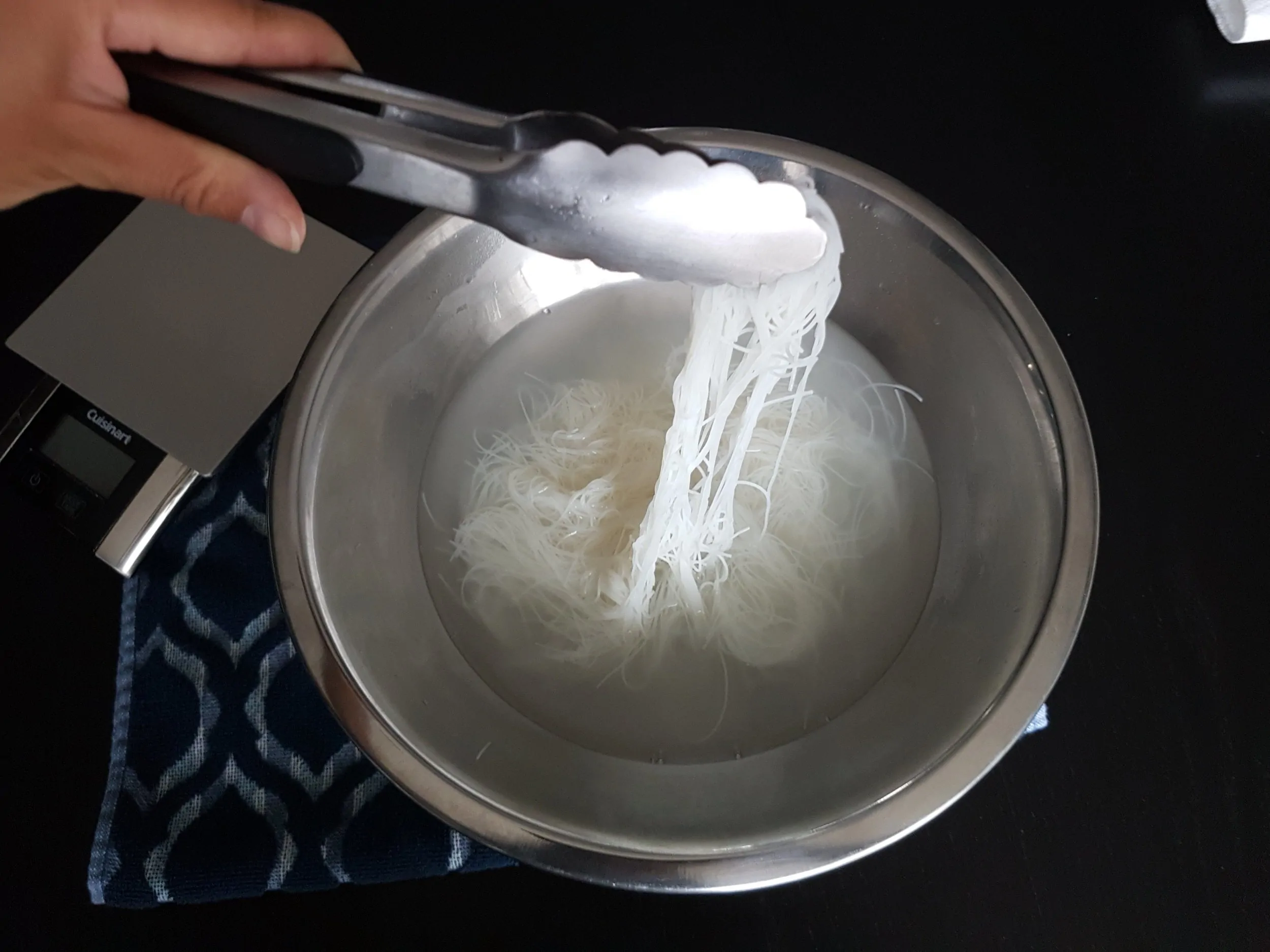 Thin rice noodles being soaked in a bowl.