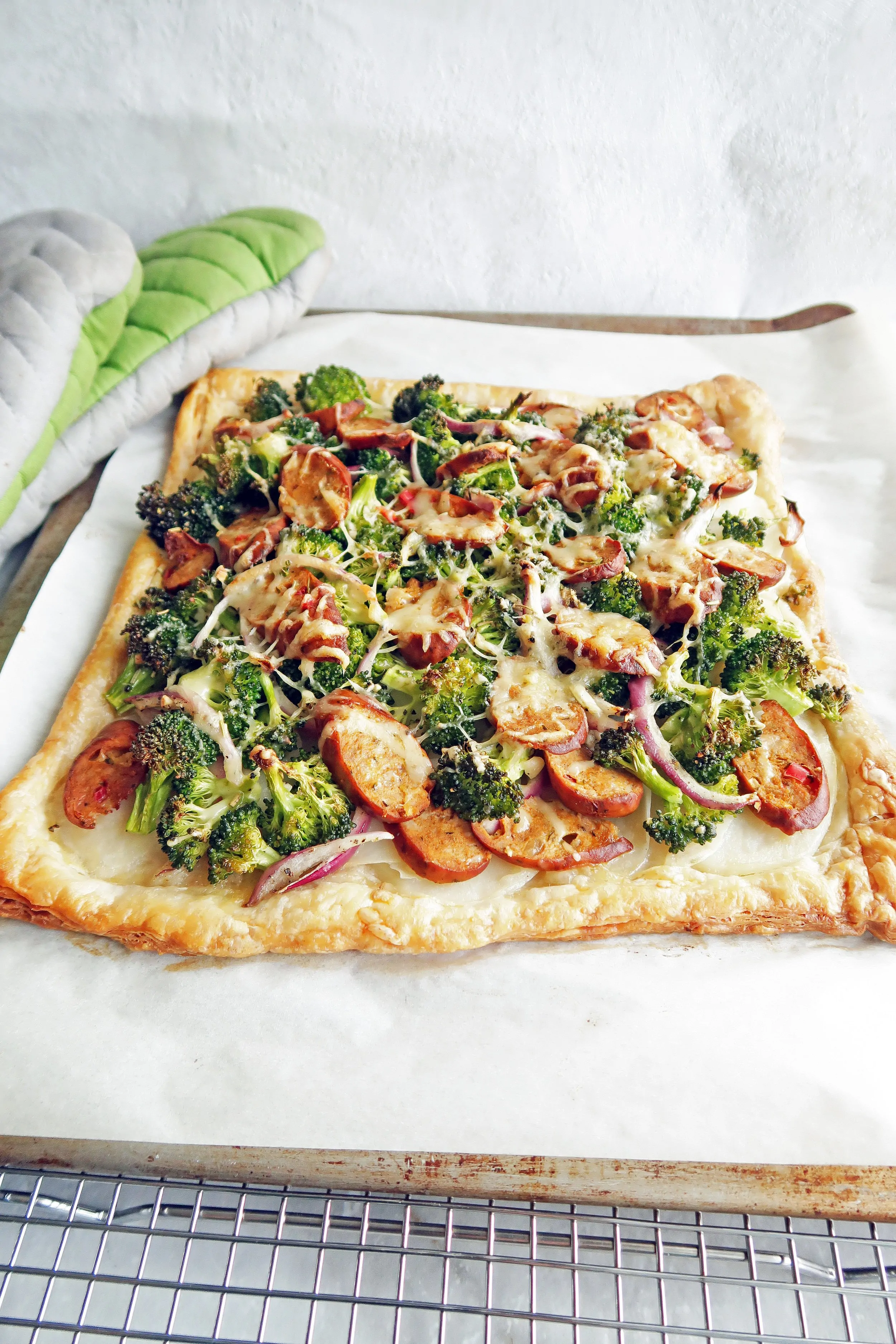 Roasted Broccoli Potato and Sausage Puff Pastry Tart on a parchment lined baking sheet.