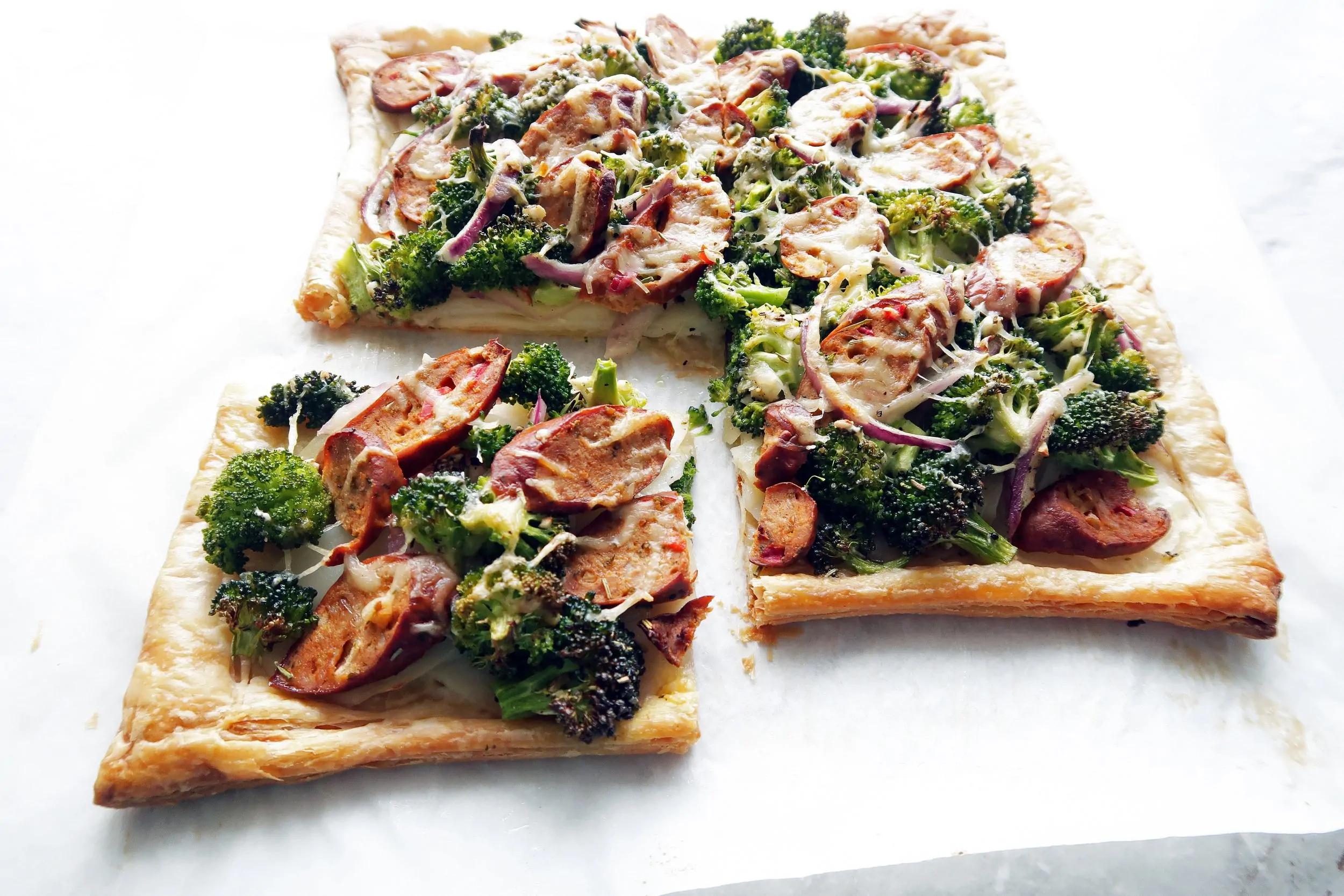 Roasted Broccoli Potato & Sausage Tart with one piece cut out; An easy to make puff pastry appetizer or dinner.