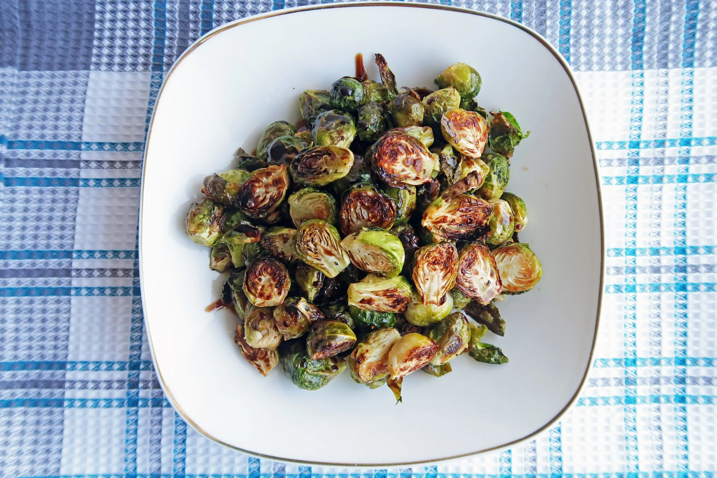 Gluten-free and vegan Roasted Brussels Sprouts with Balsamic-Maple Glaze piled on a white plate.