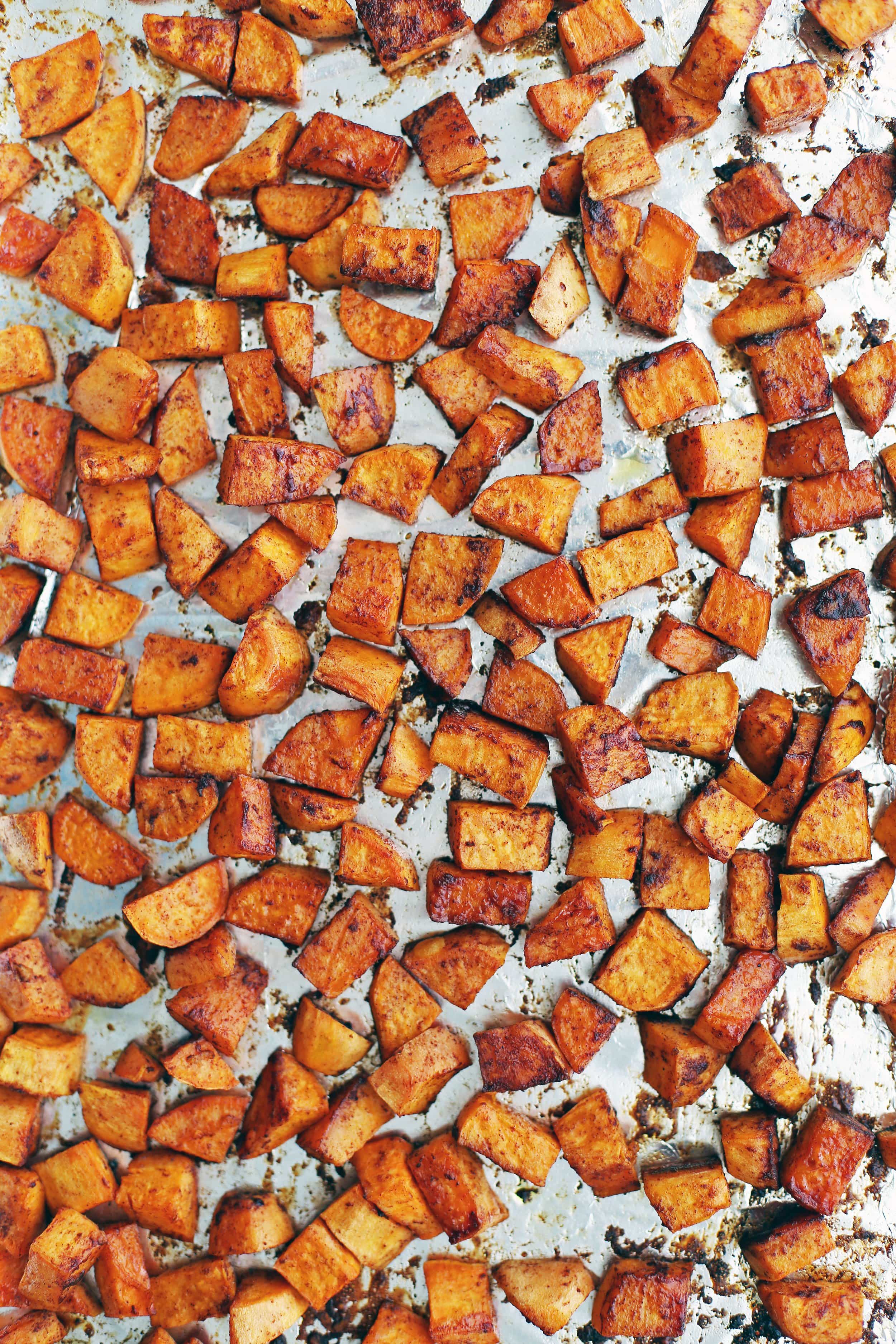 Roasted maple cinnamon sweet potato pieces in a single layer on a baking sheet.