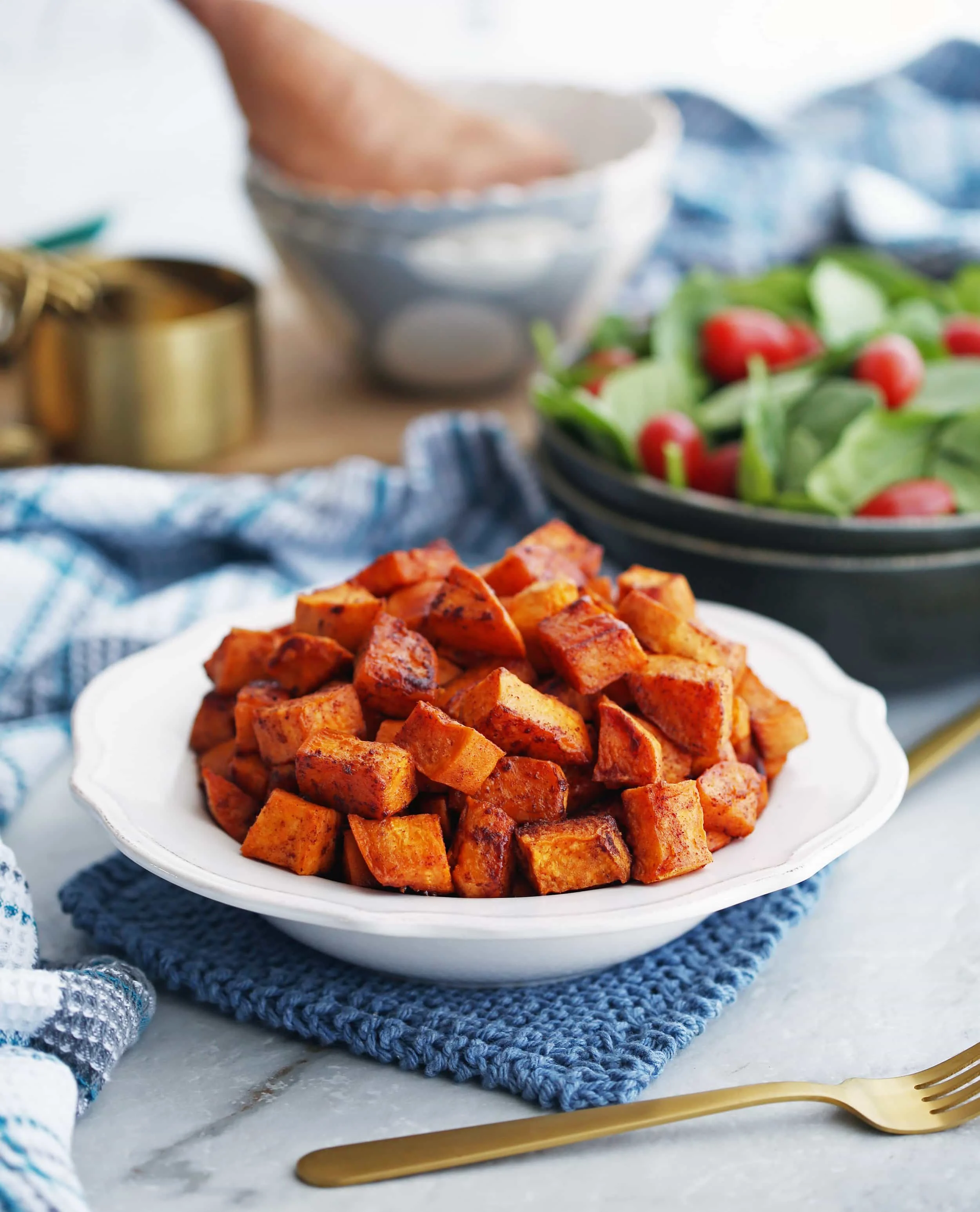 Vegan and gluten-free roasted maple cinnamon sweet potatoes pieces in a white bowl.