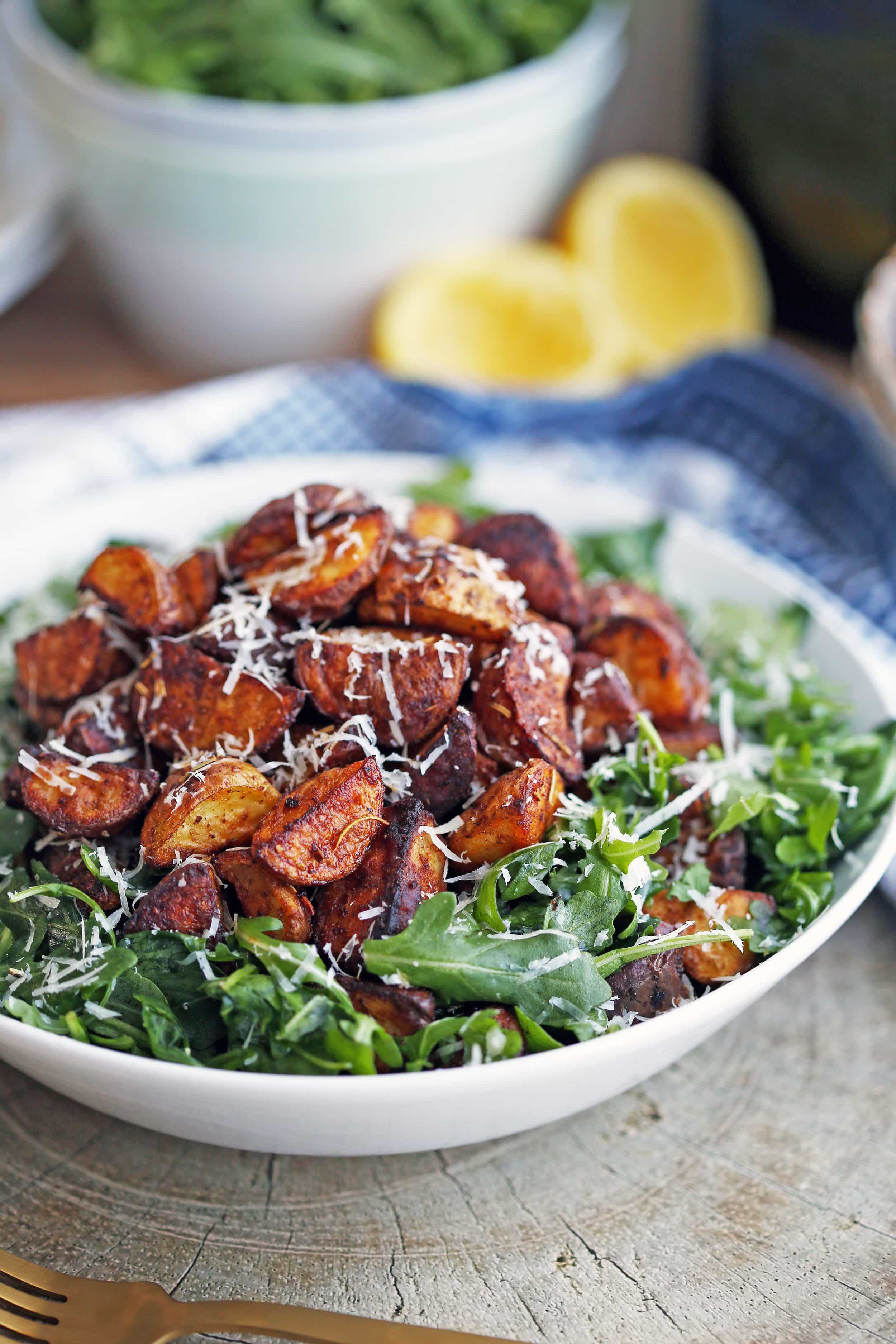 Crispy roasted potatoes with baby arugula salad in a white bowl.