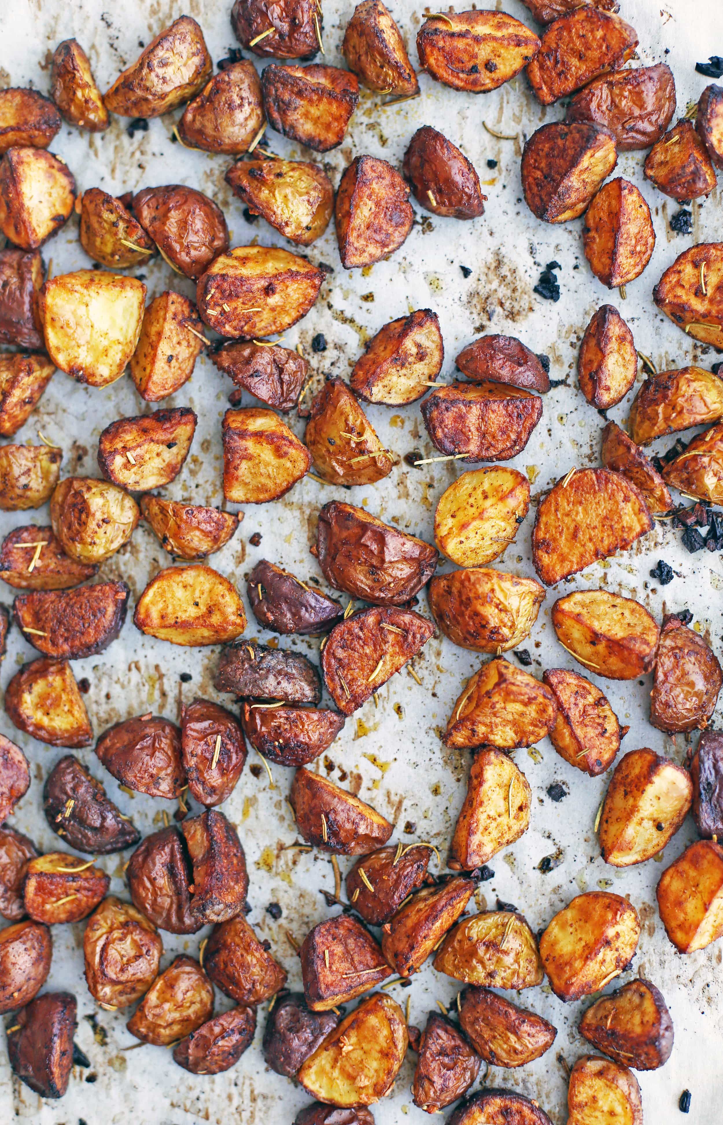 Chopped roasted spiced baby potatoes in a parchment paper lined baking sheet.