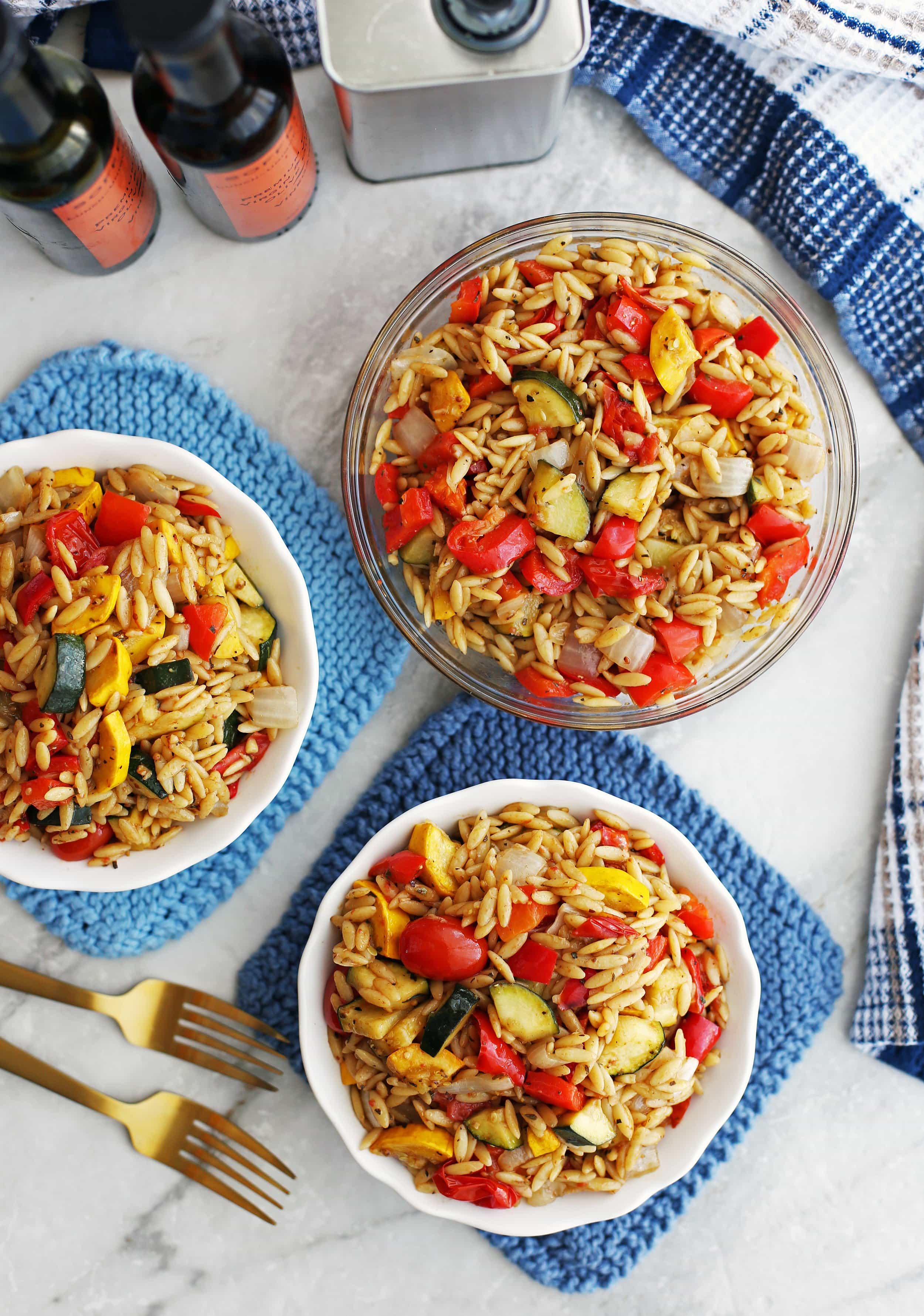 Three bowls containing colourful roasted summer vegetable and orzo pasta salad with Dijon-balsamic vinaigrette.