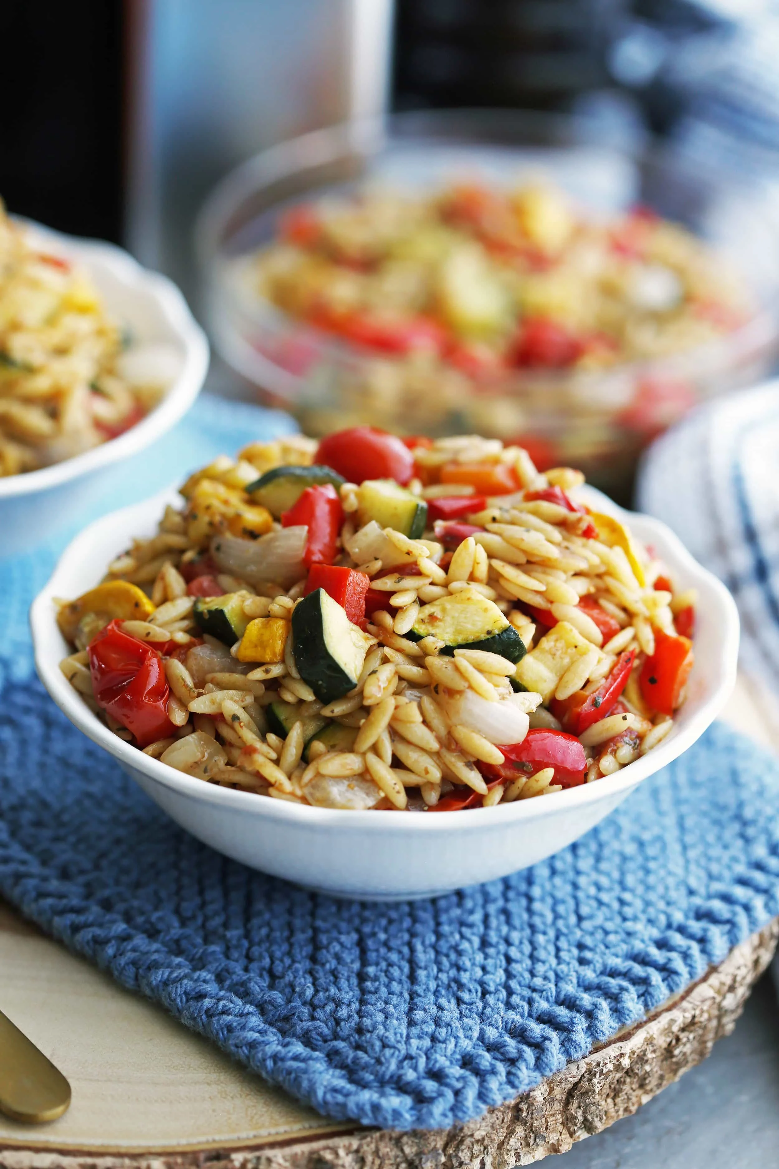A small white bowl containing Roasted summer vegetable and orzo pasta salad with Dijon-balsamic vinaigrette