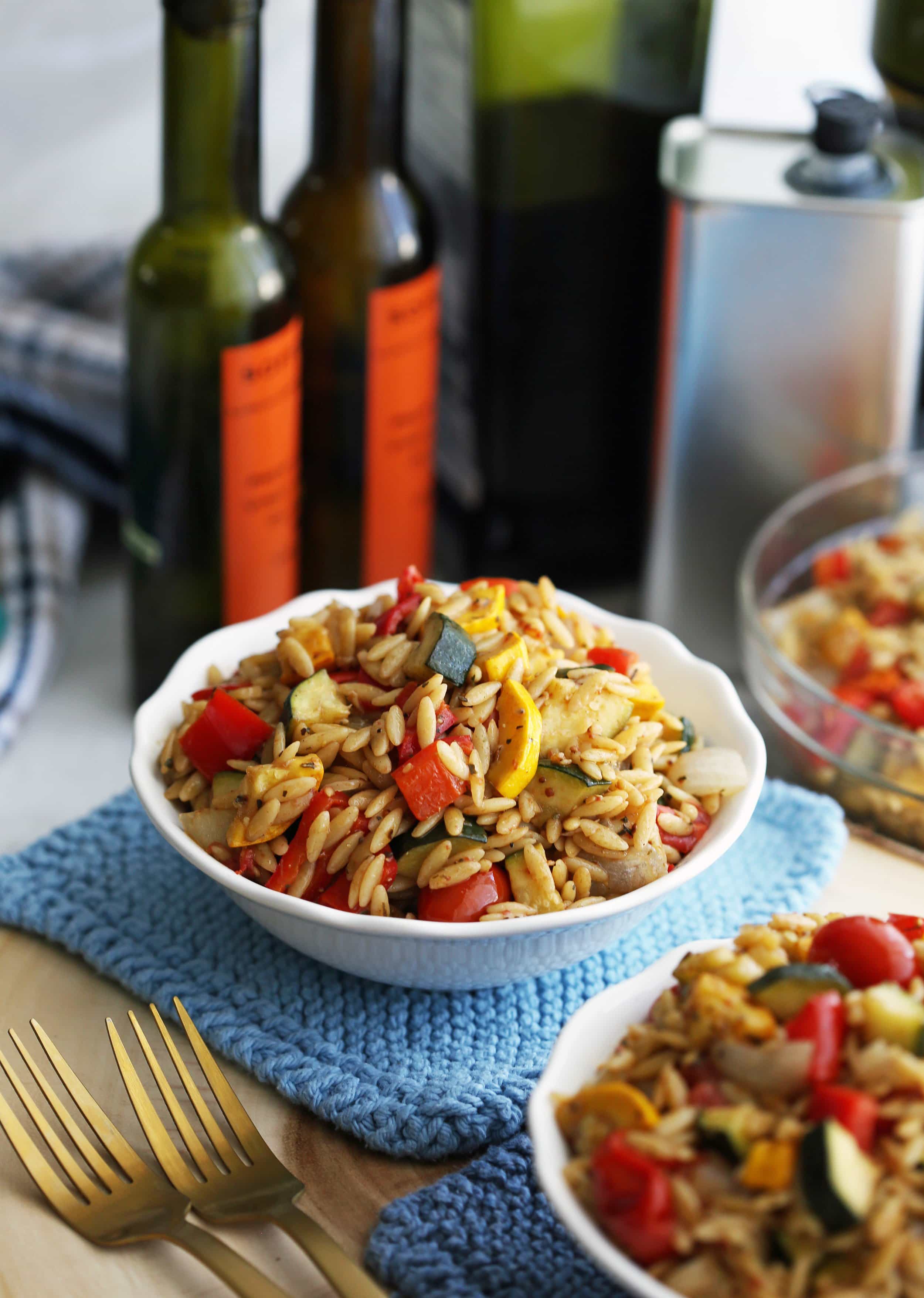 Roasted summer vegetable and orzo pasta salad with Dijon-balsamic vinaigrette in a small white bowl.