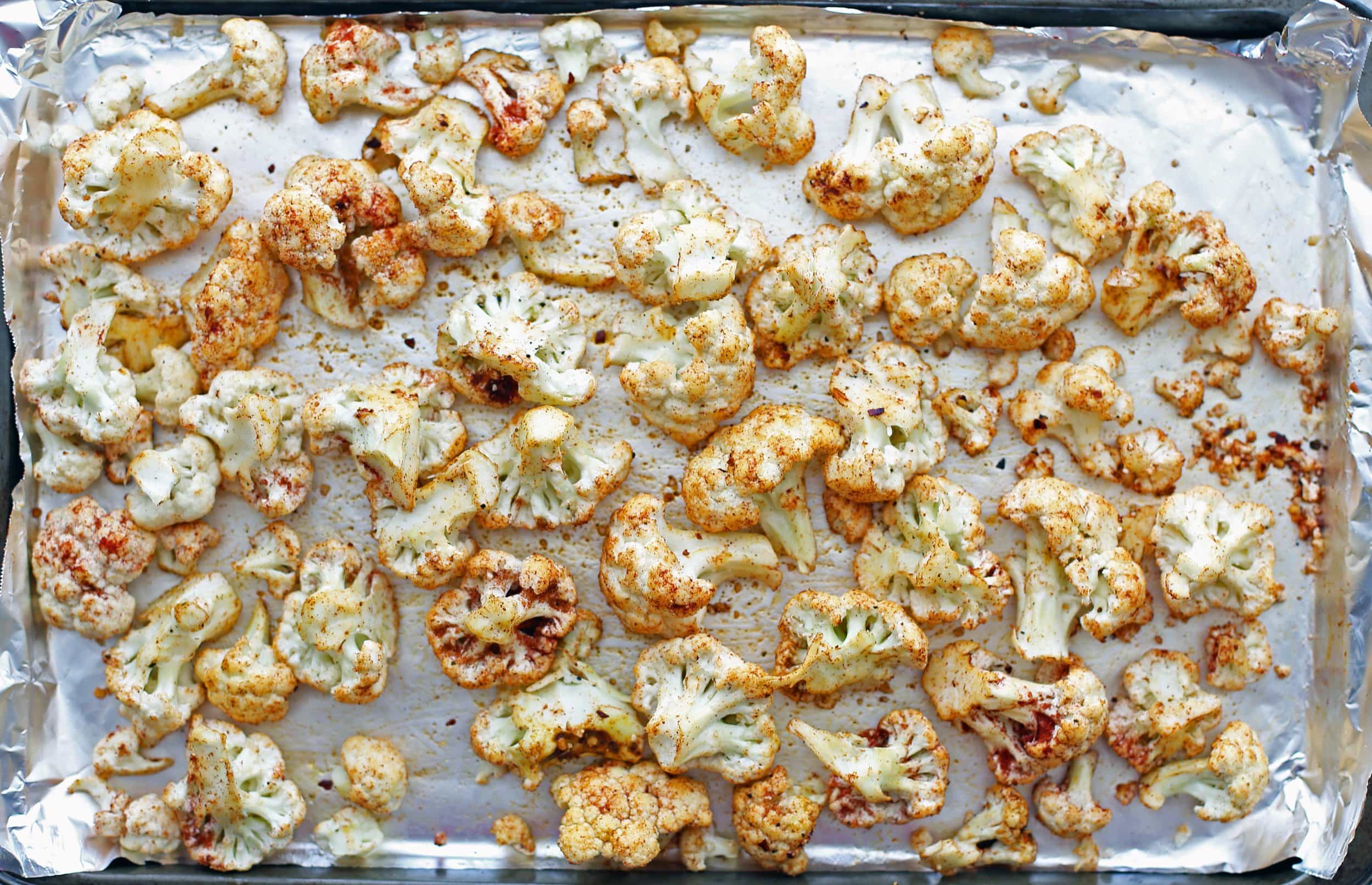 Cauliflower covered with spices and oil and spread in a layer on a baking sheet lined with aluminum foil.