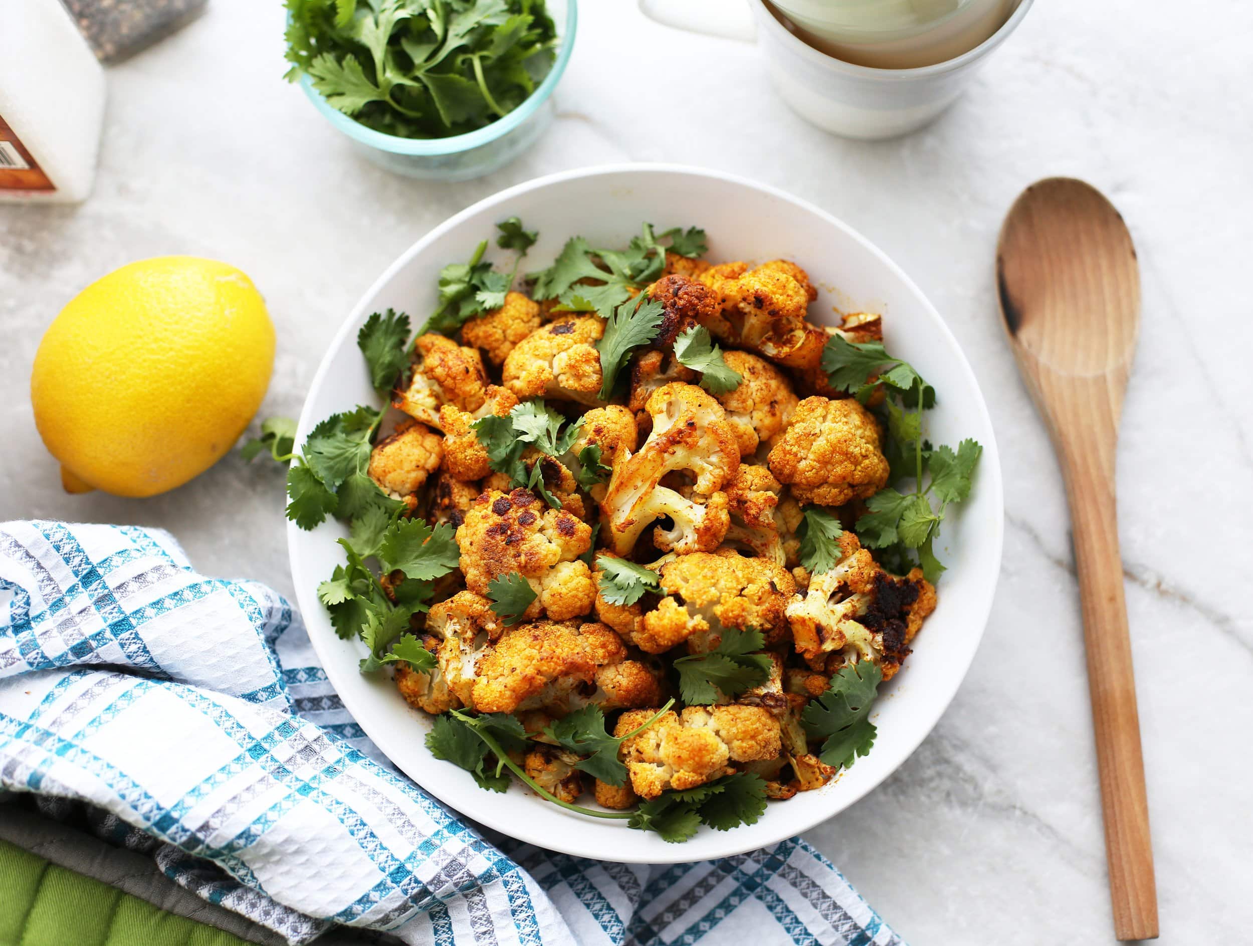 Overhead view of a wide bowl full of roasted spicy cauliflower with fresh cilantro.