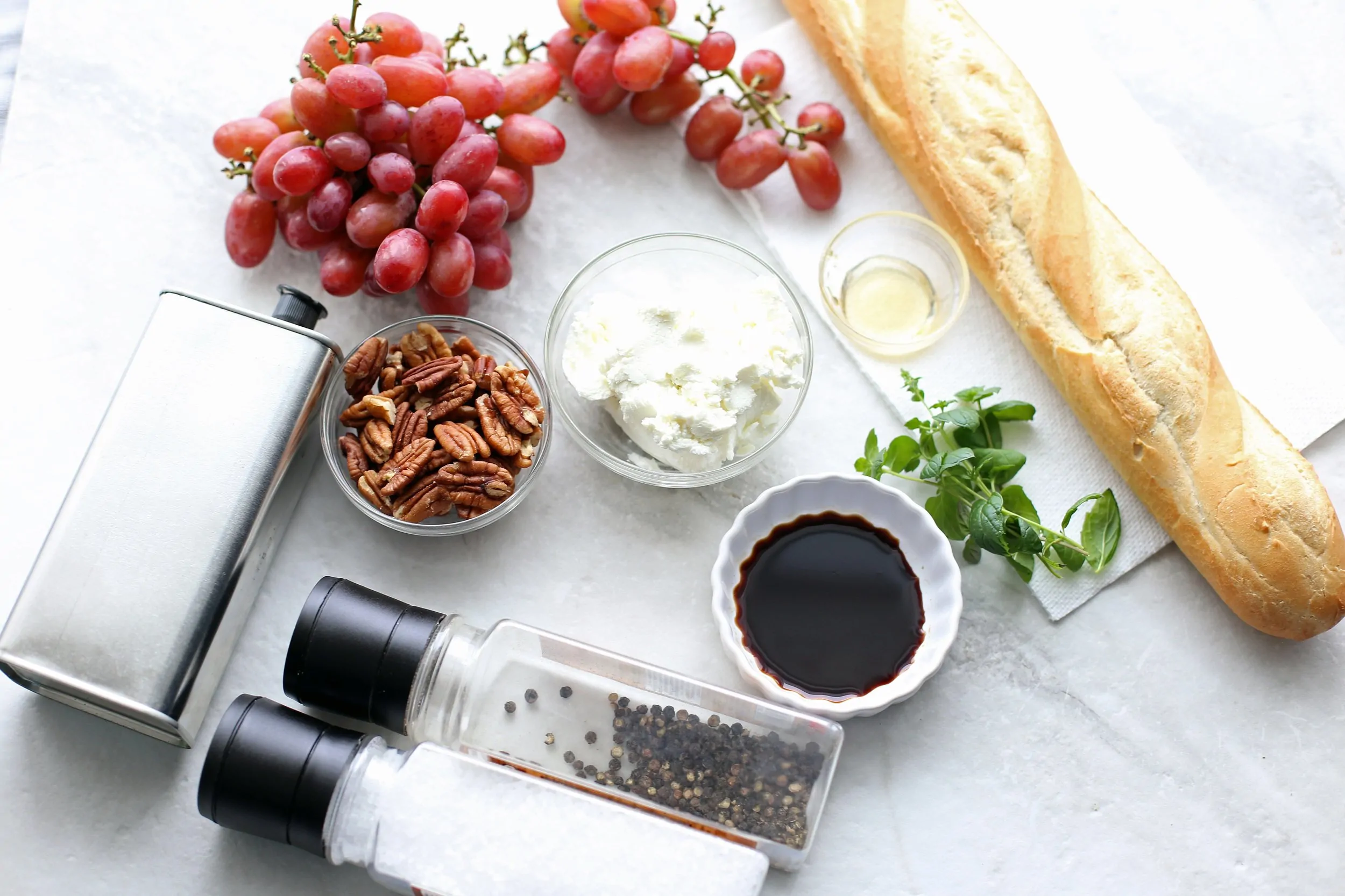 Overview of a baguette, red grapes, goat cheese, balsamic vinegar, fresh mint, pecans, olive oil, salt, and pepper.