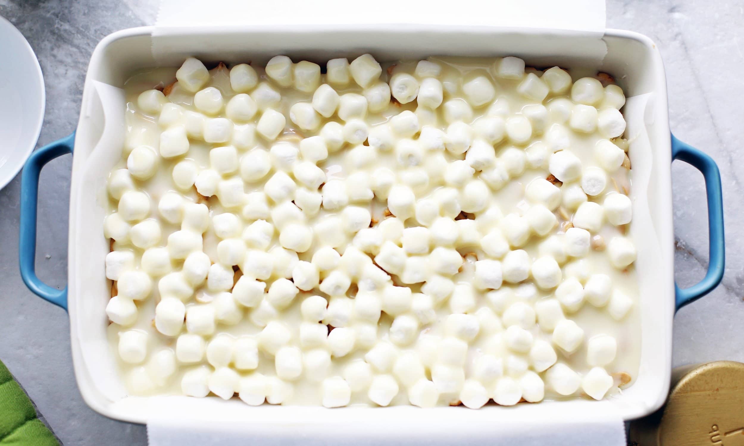 Overhead shot of pre-baked rocky road magic bars that has marshmallows and condensed milk on top.