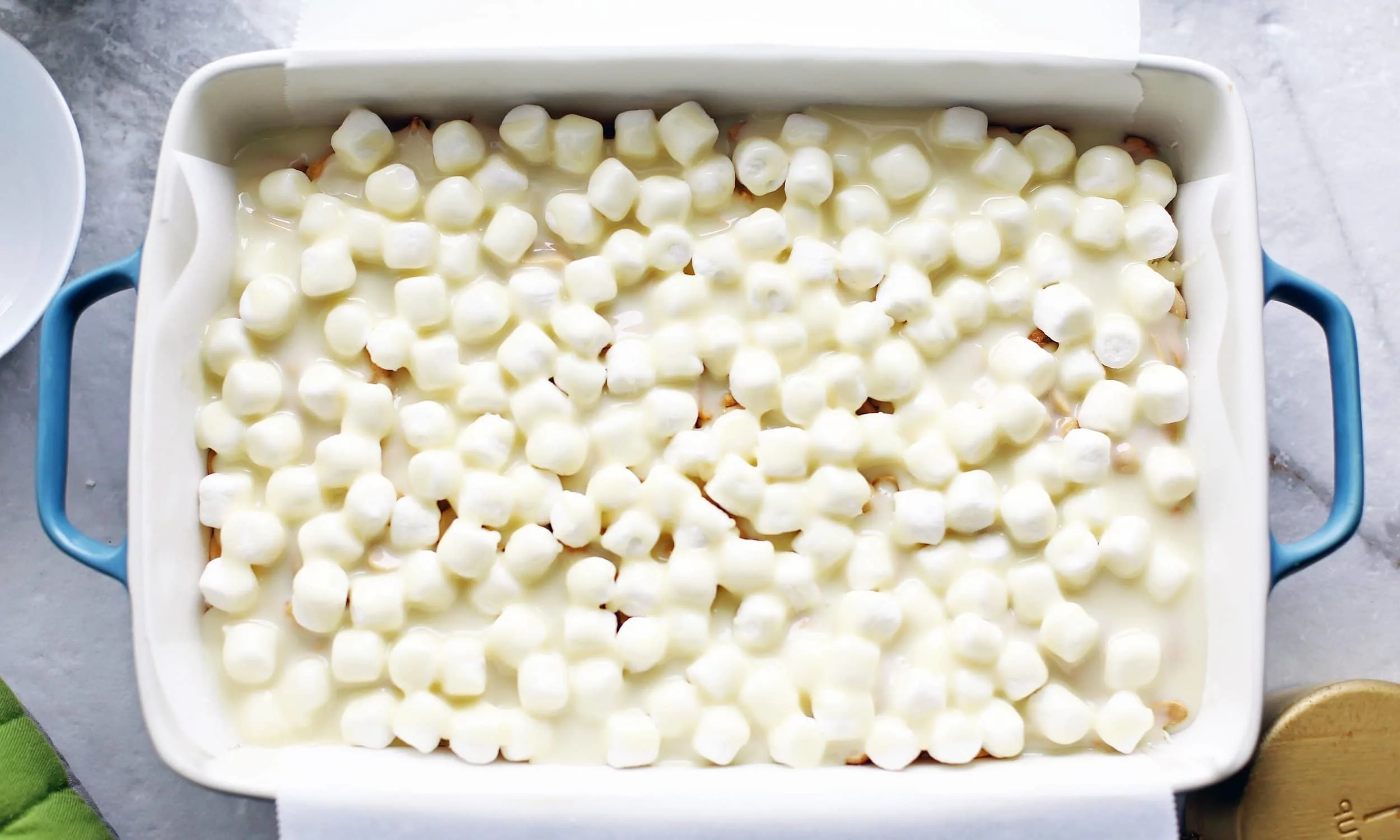 Overhead shot of pre-baked rocky road magic bars that has marshmallows and condensed milk on top.