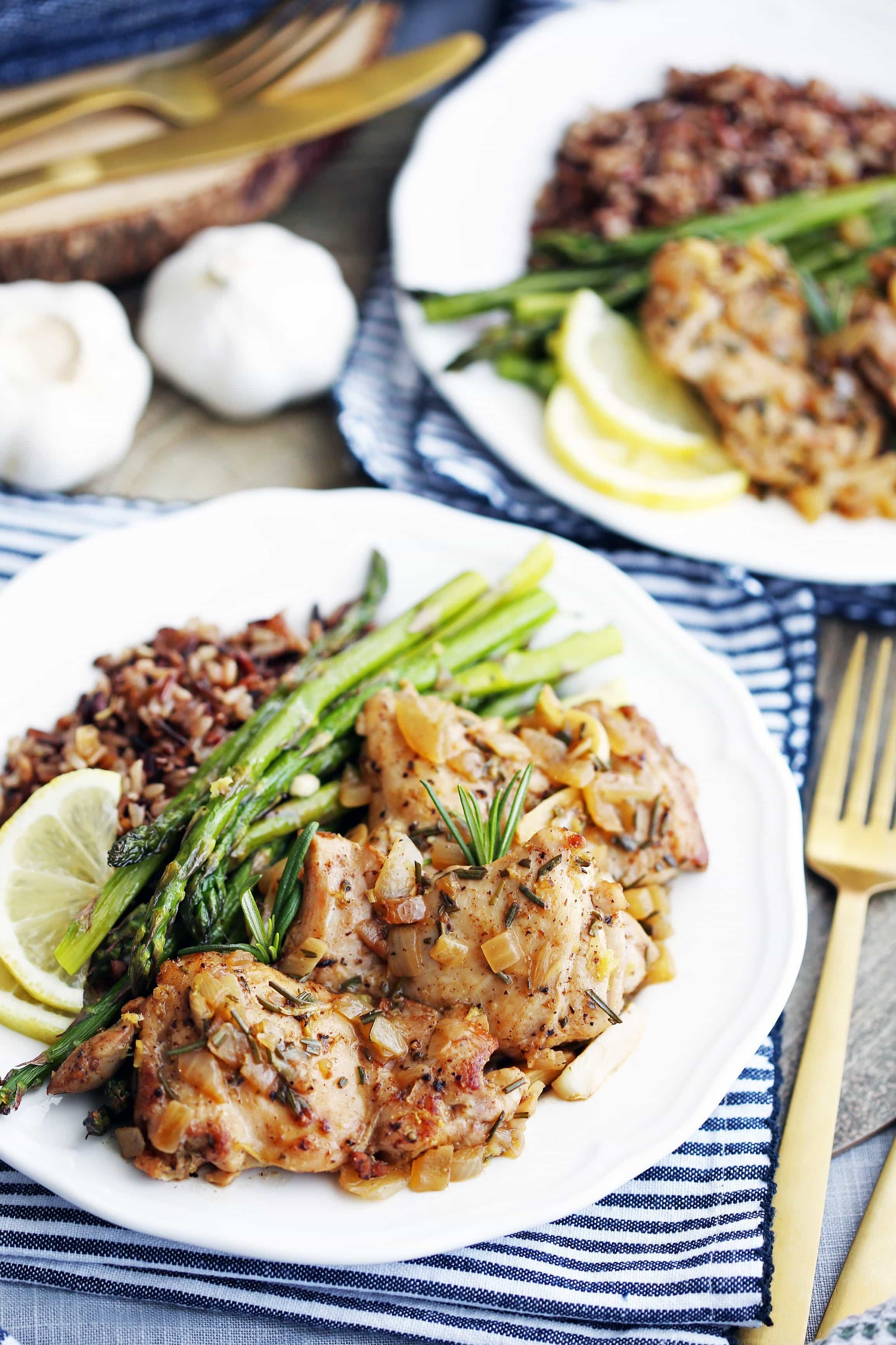 A white plate containing rosemary garlic chicken, roasted asparagus, and wild rice.