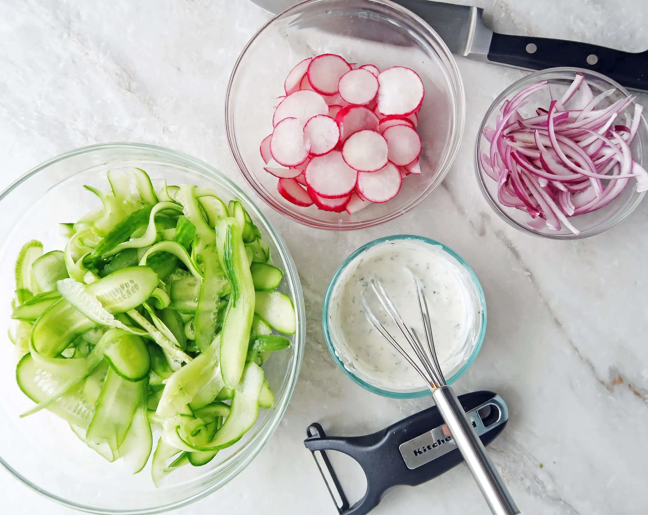 Bowls of shaved cucumbers, radishes,sliced red onions, and lime-mint yogurt dressing.