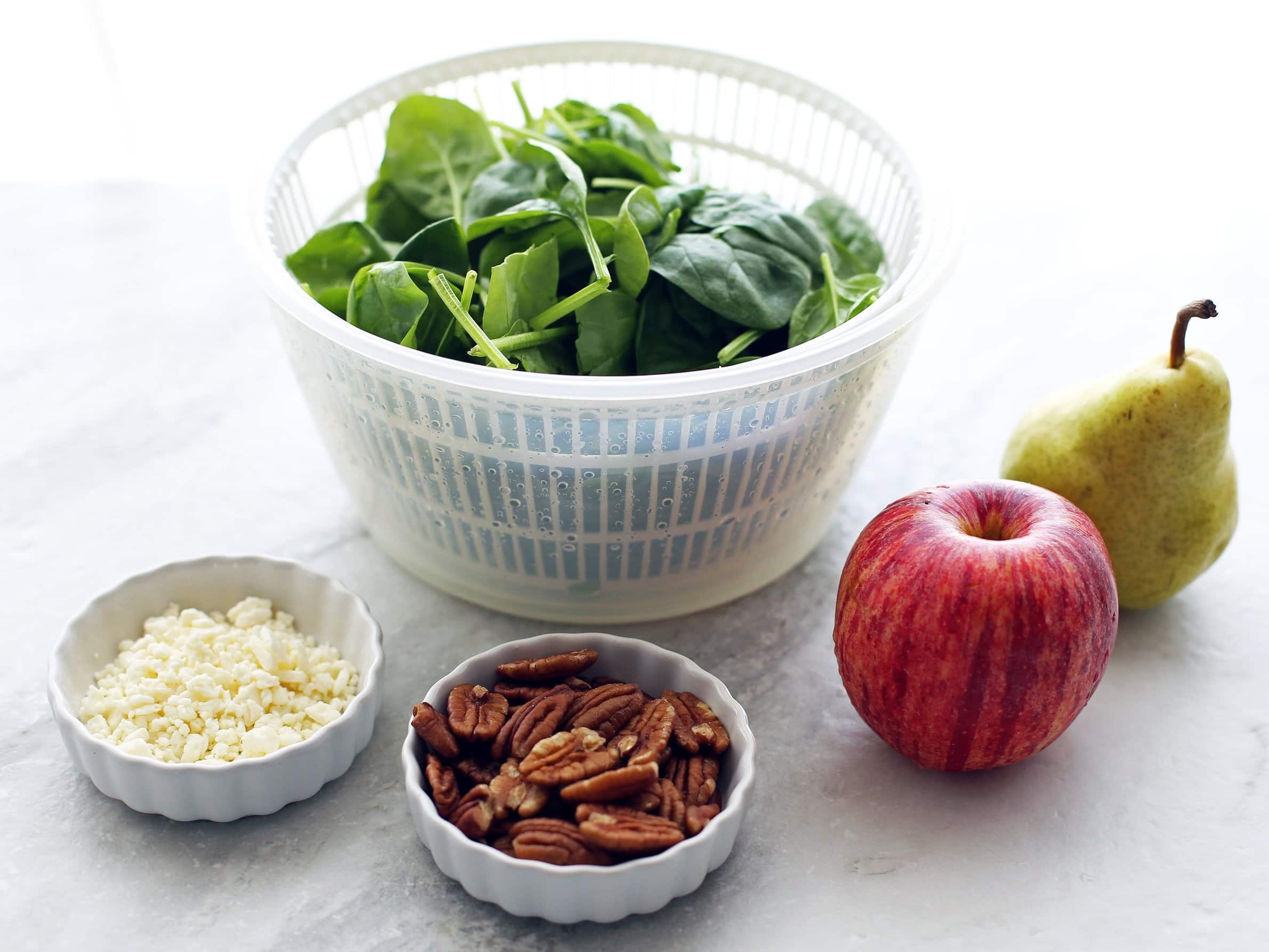 Side view of pecans, feta cheese, spinach, apple, and pear.