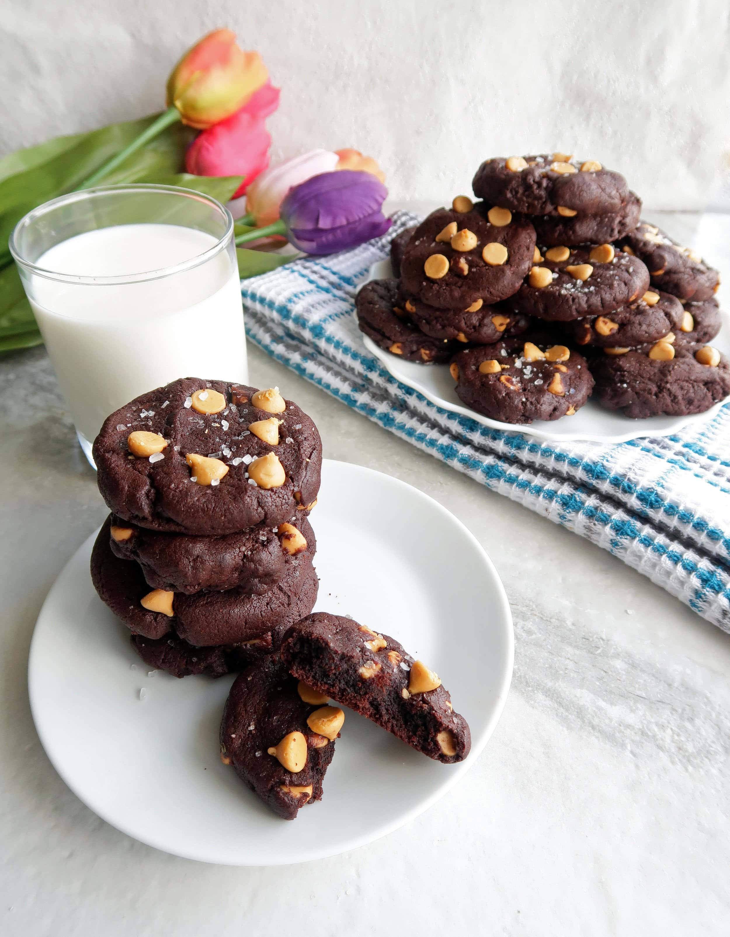 Salted chocolate butterscotch chip cookies stacked on top of one another on two separate plates.
