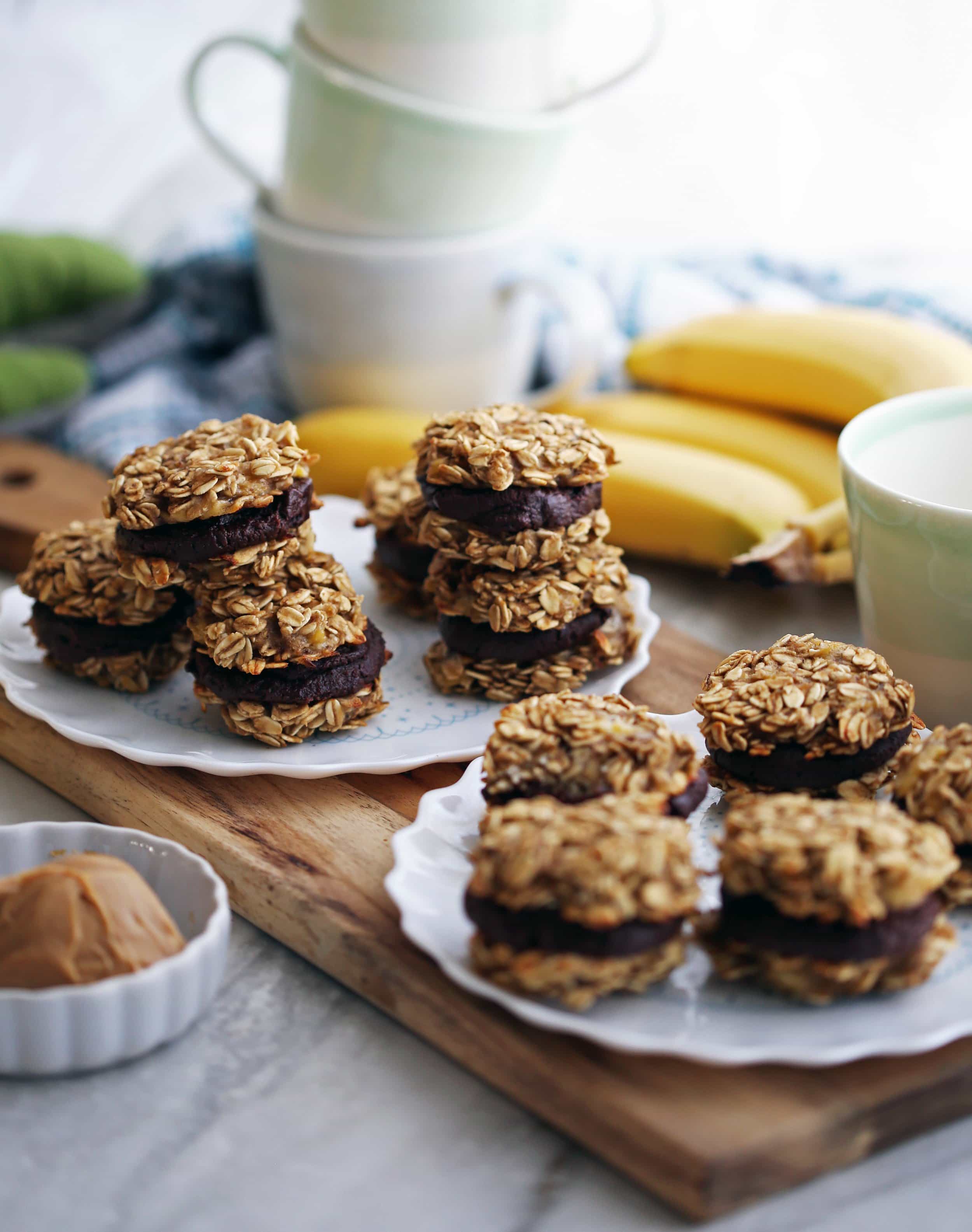 Side view of two plates of banana oatmeal sandwich cookies with peanut butter cocoa filling.