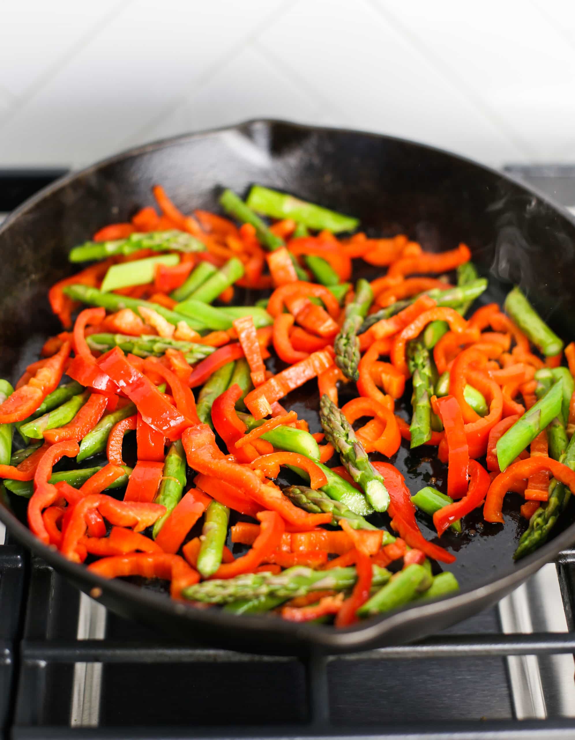 Sautéed chopped asparagus and red bell pepper in a cast iron skillet.