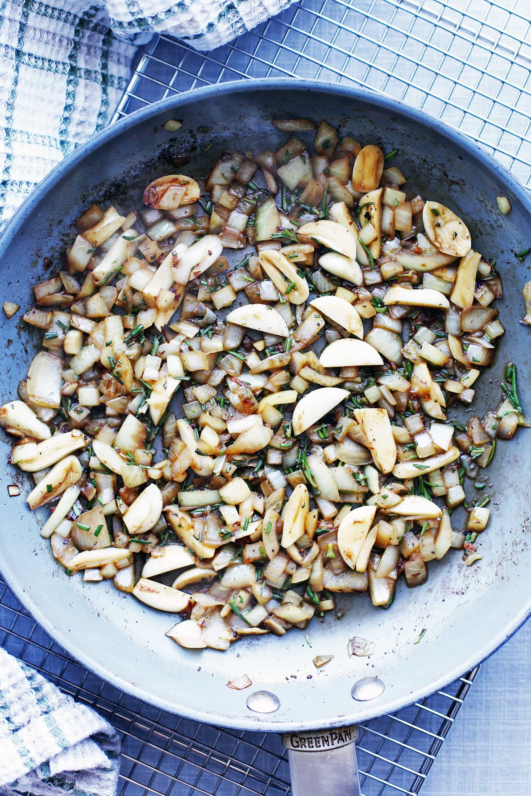 Sautéed garlic and onions and minced rosemary in a large blue pan.