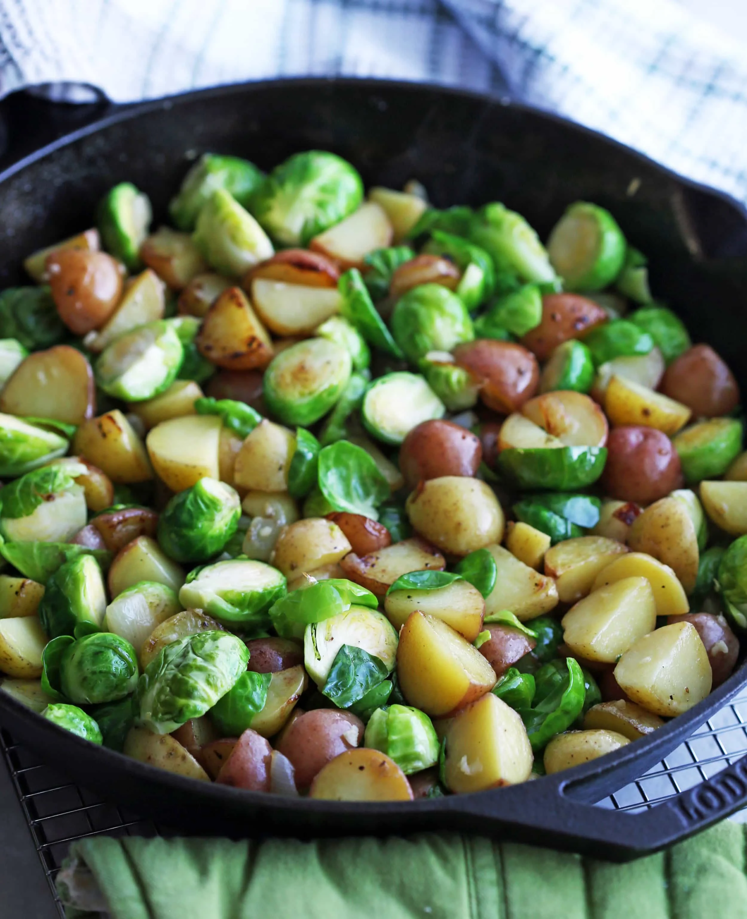 Sautéed onions, chopped baby potatoes, and halved Brussels sprouts in a cast iron skillet.